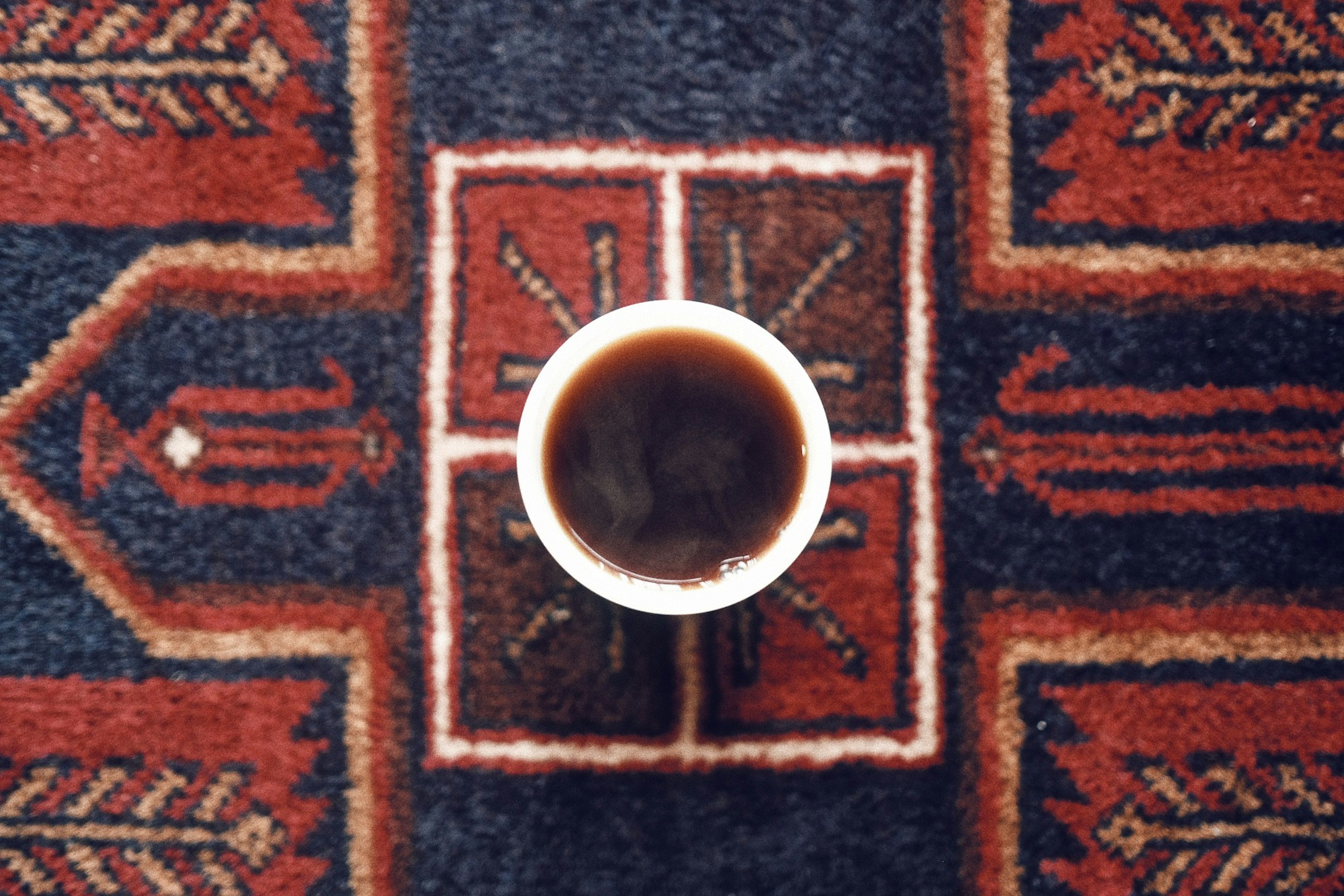 Una taza de café colocada sobre una alfombra decorativa