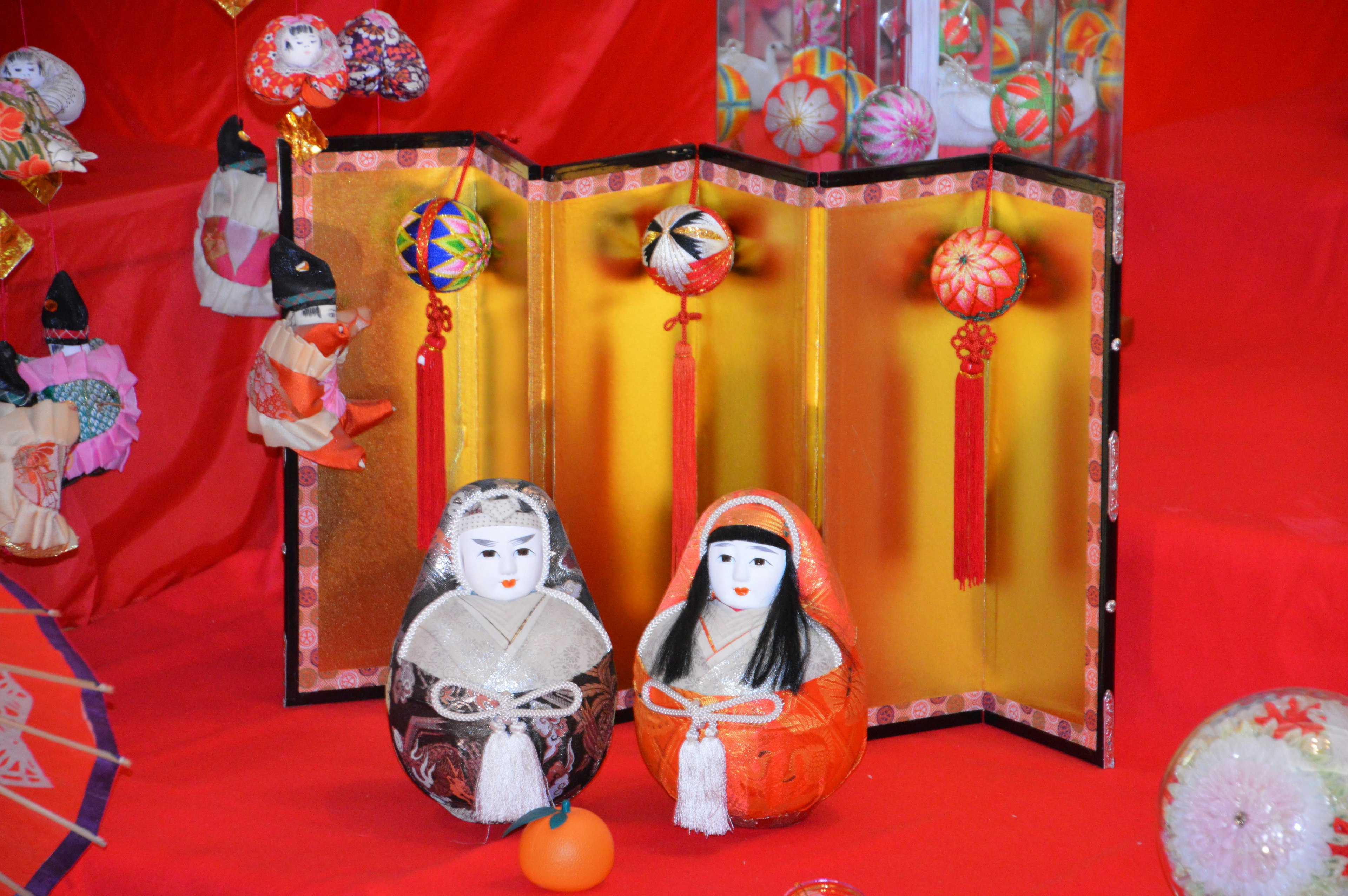 Muñecas hina japonesas tradicionales con elementos decorativos sobre un fondo rojo