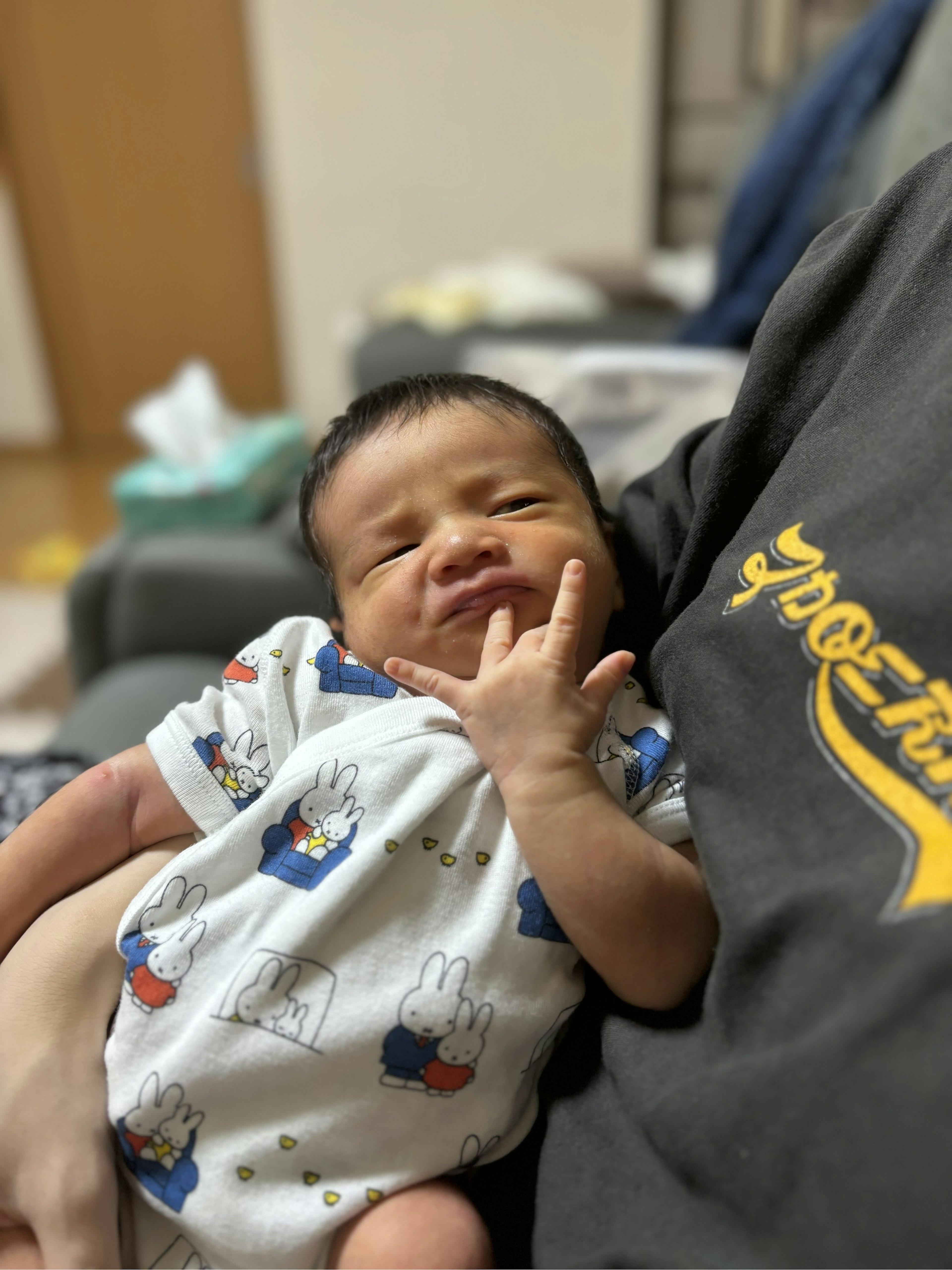 Un bébé mignon faisant un geste de la main en étant tenu