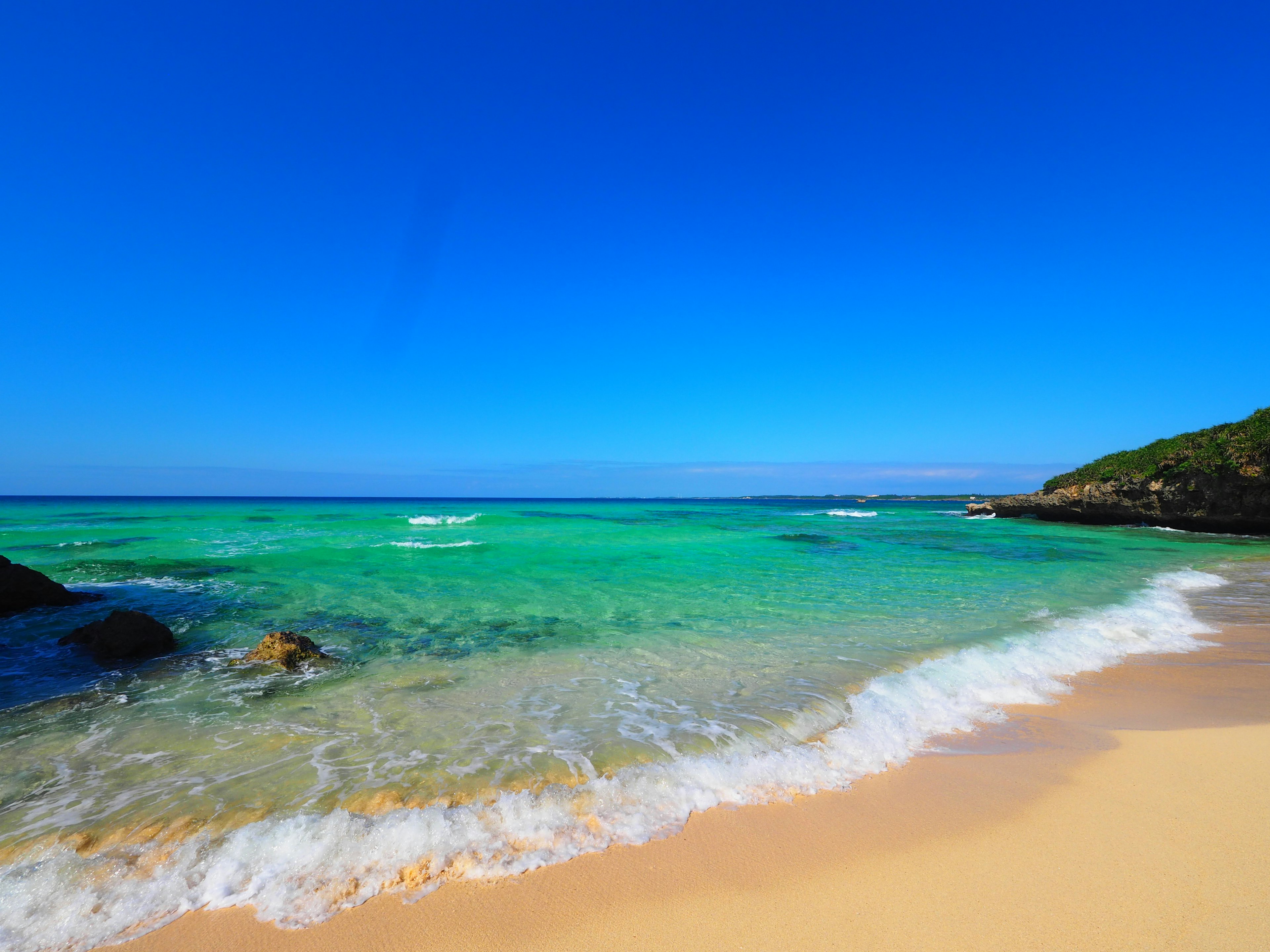 ทิวทัศน์ชายหาดที่มีท้องฟ้าสีฟ้าและมหาสมุทรสีเขียว