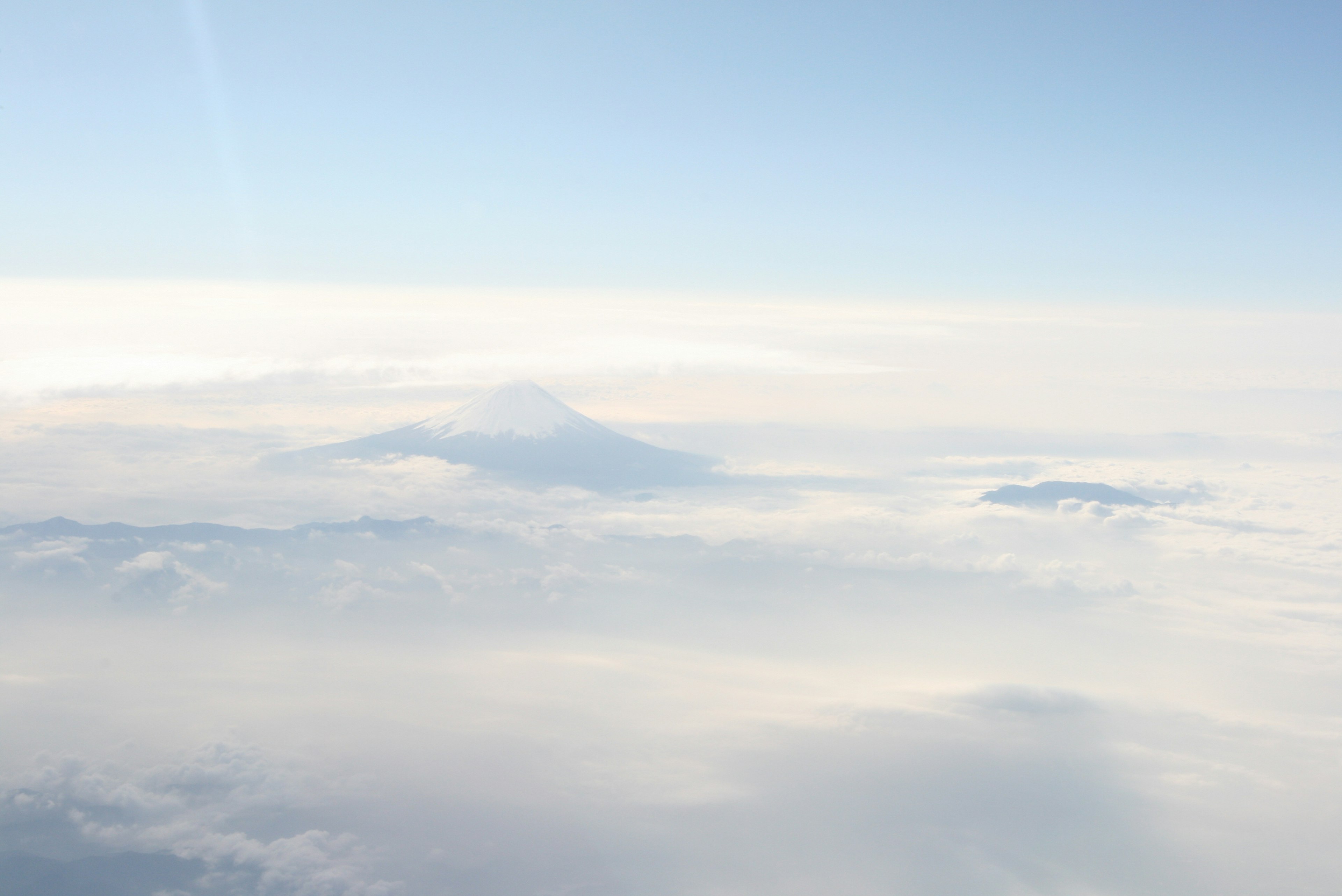 Sommets de montagne émergeant d'une mer de nuages sous un ciel bleu clair