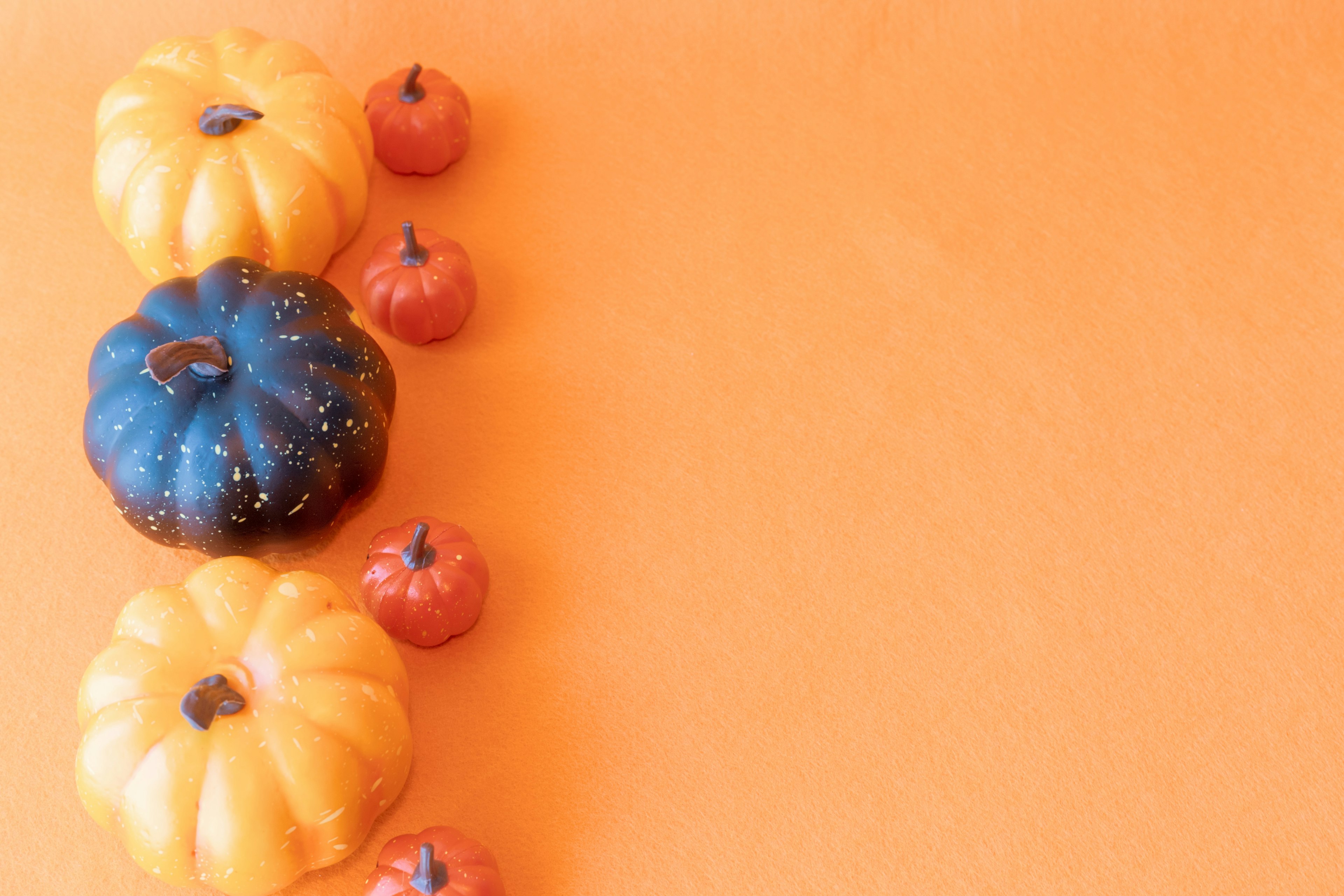 Calabazas amarillas y negras con pequeñas calabazas rojas sobre un fondo naranja