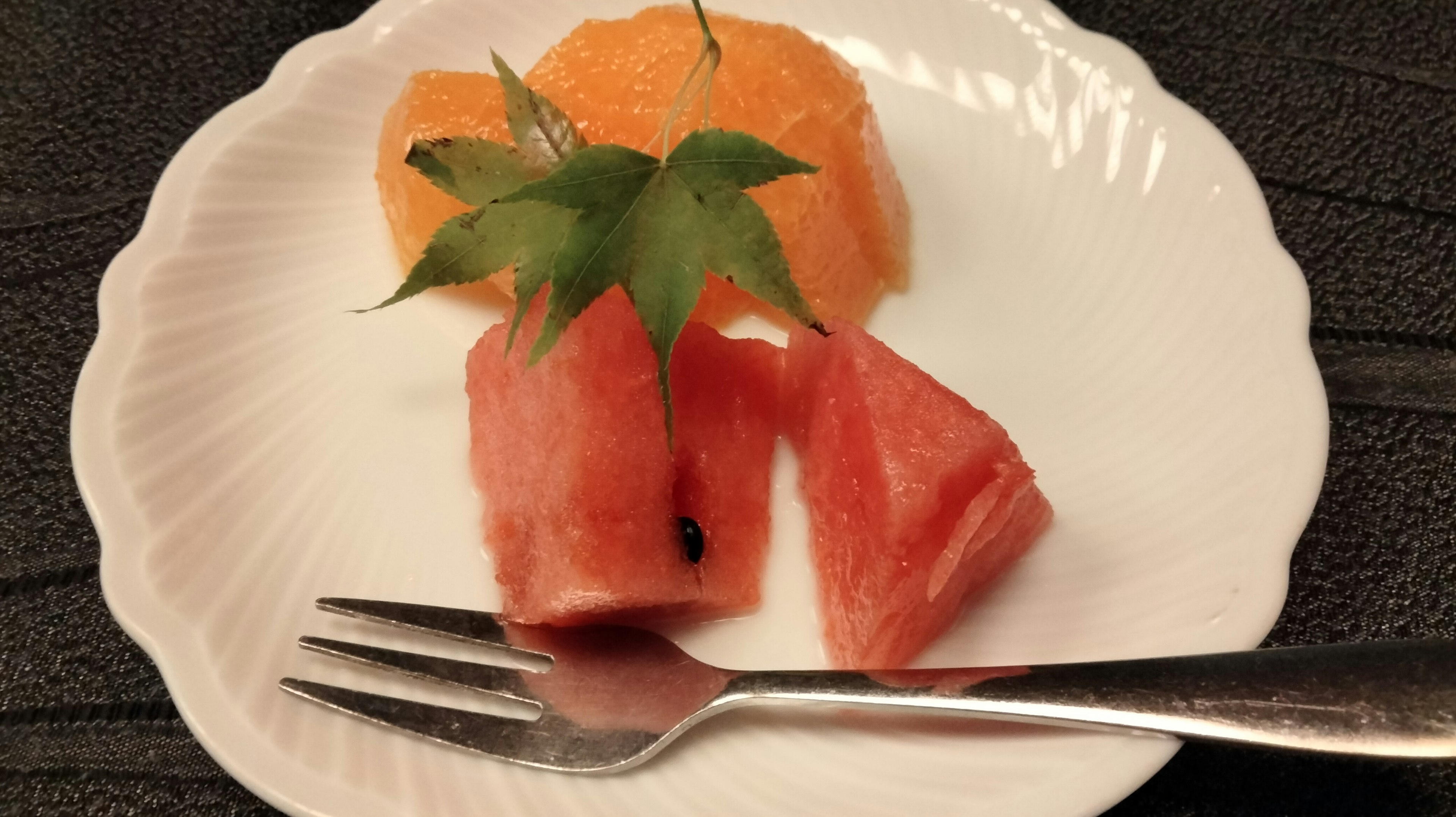 Arreglo de frutas de sandía y naranja en un plato blanco