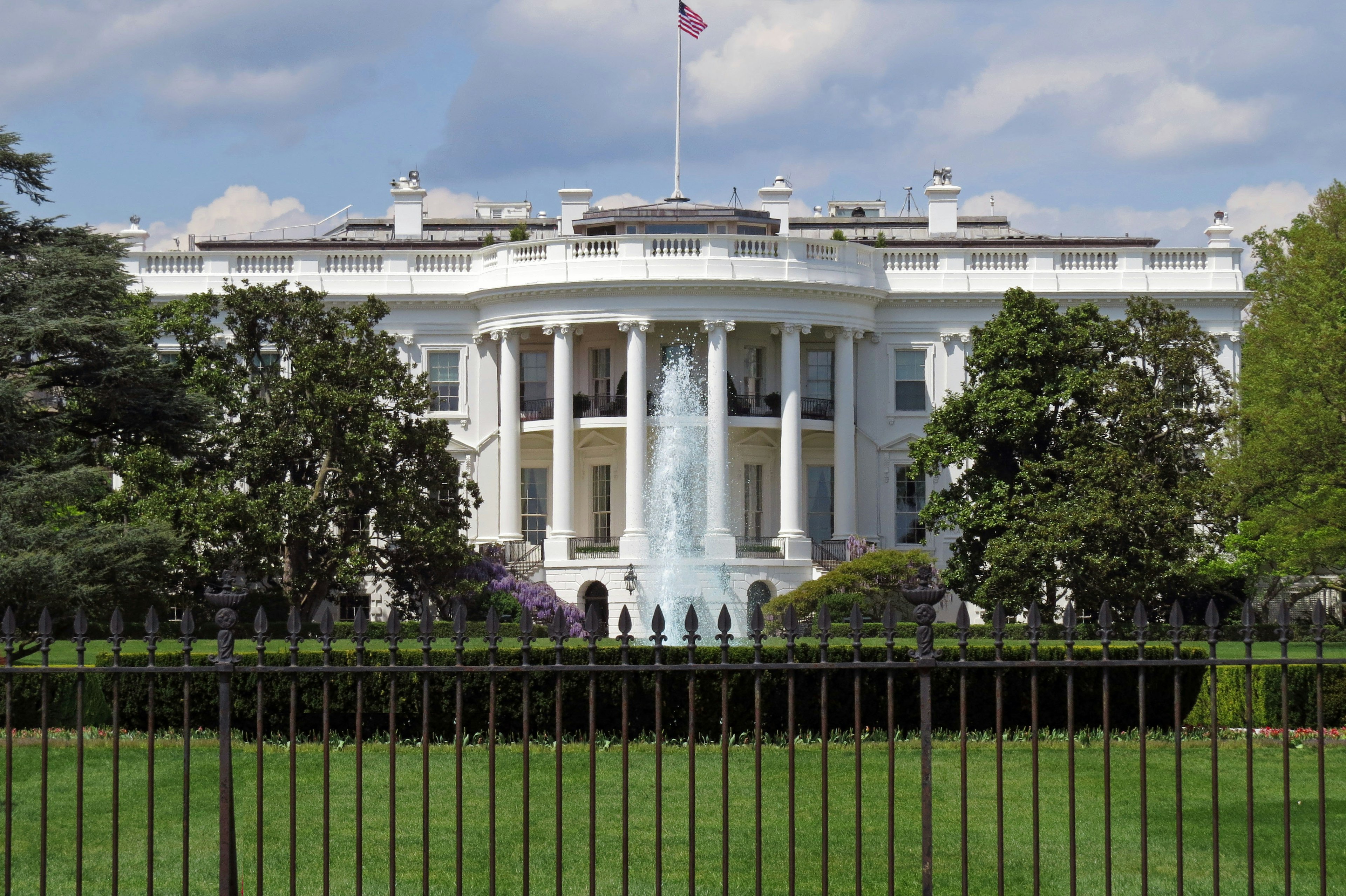 Front view of the White House with green lawn and trees