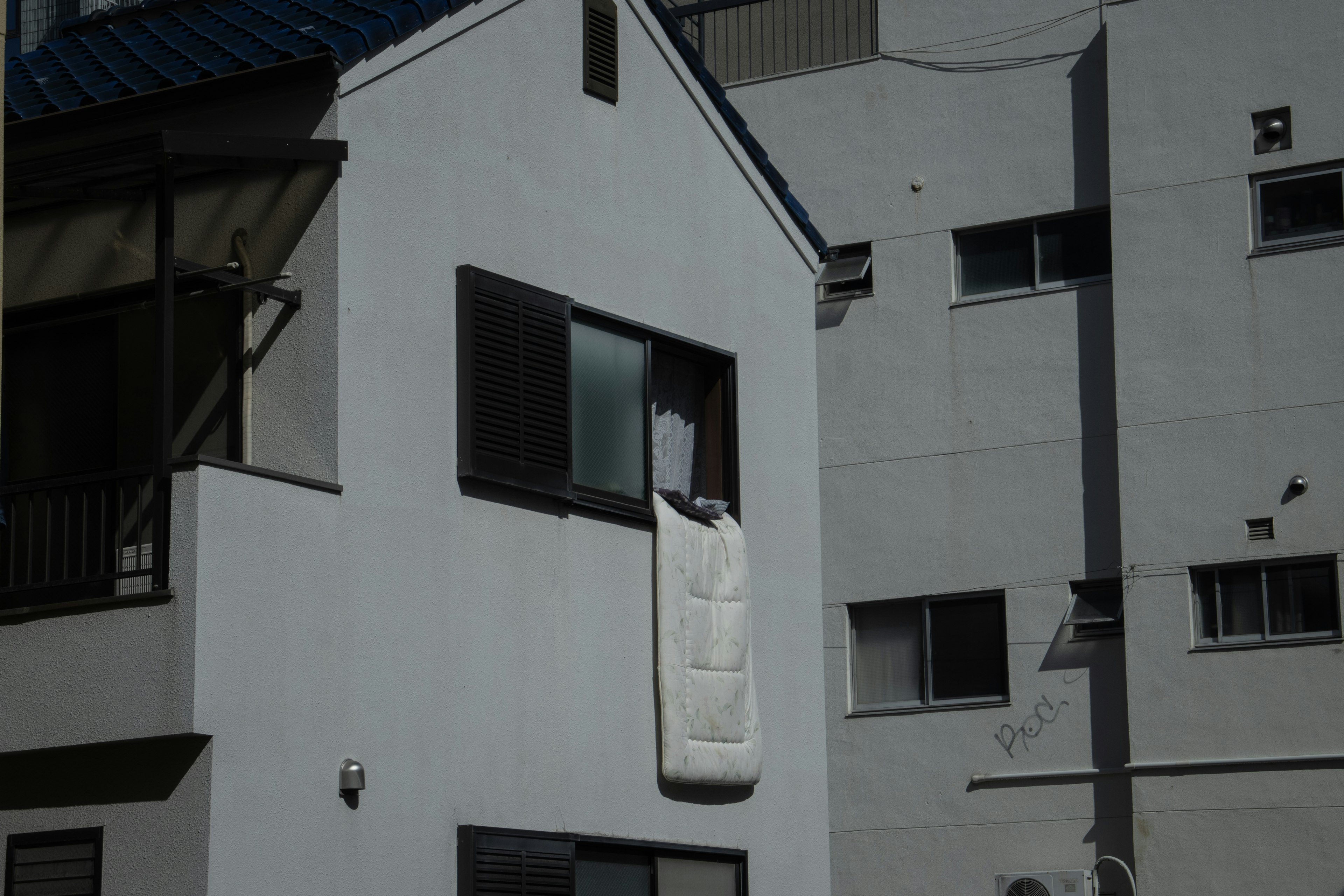 A white mattress hanging out of a window of a residential building