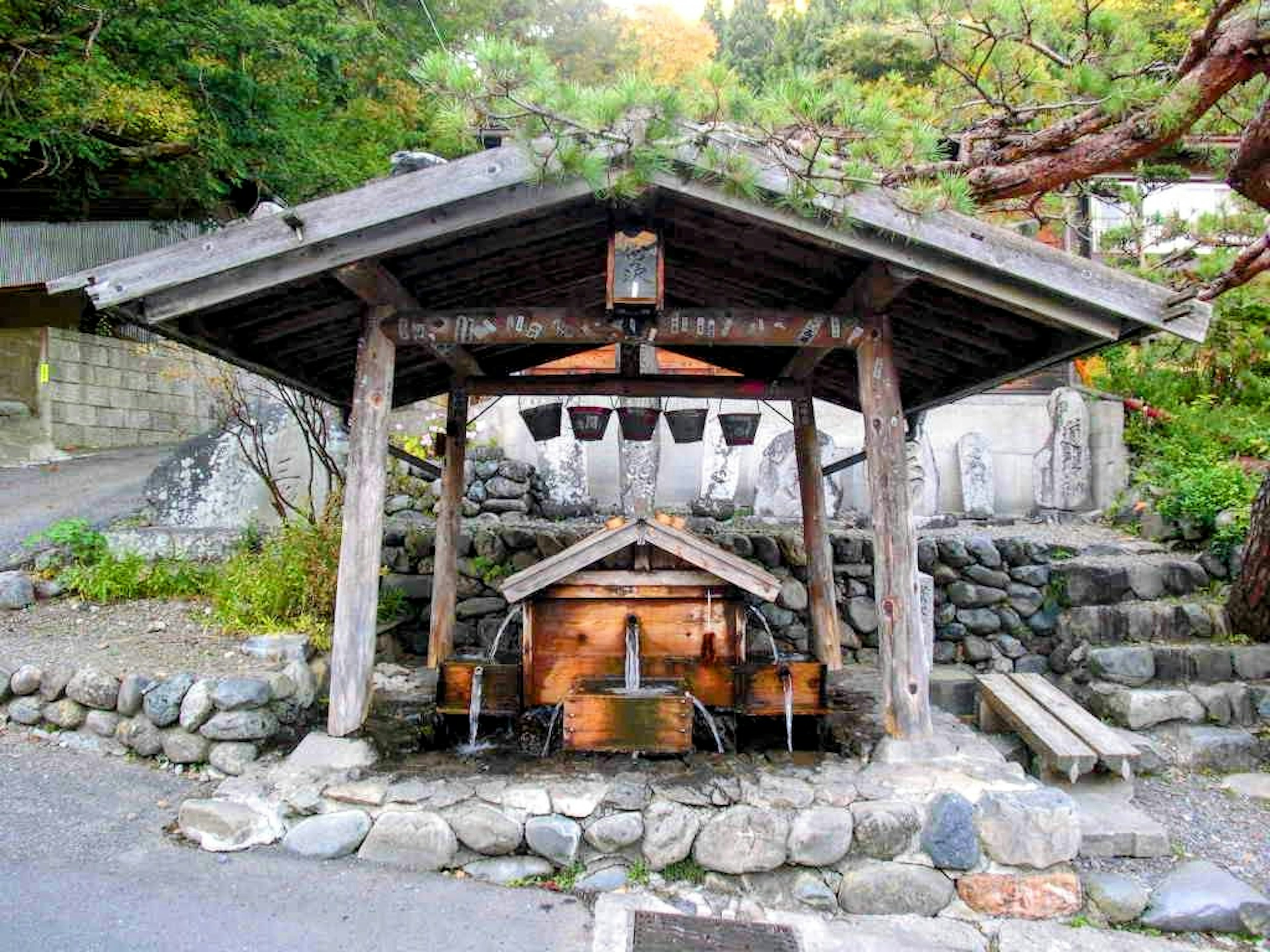 Traditional water purification station under a wooden roof with stone pathway