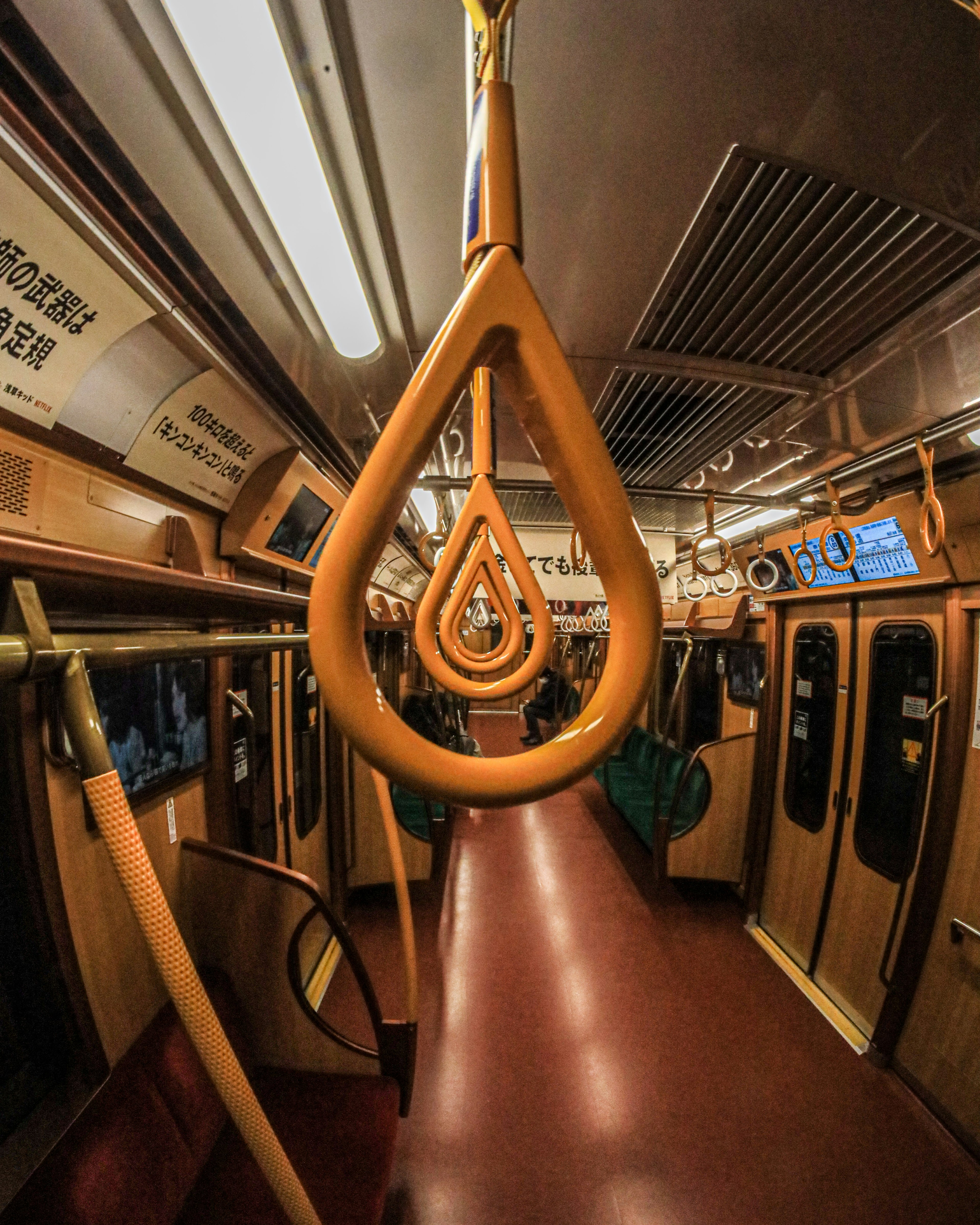 Interior kereta subway dengan pegangan oranye yang khas