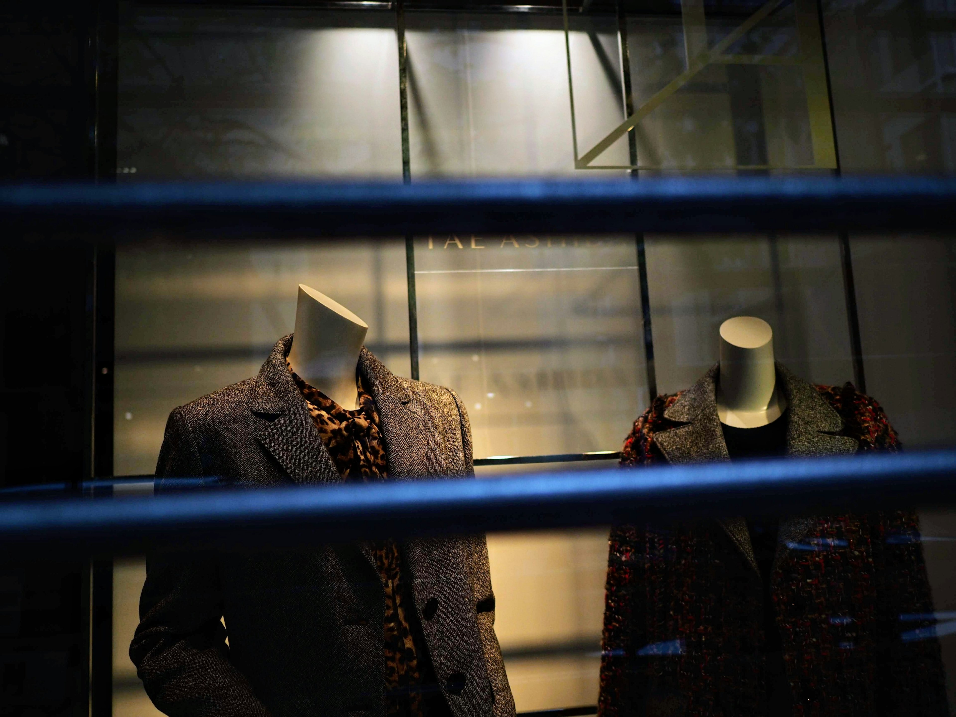 Maniquí exhibiendo abrigos y chaquetas elegantes en una vitrina