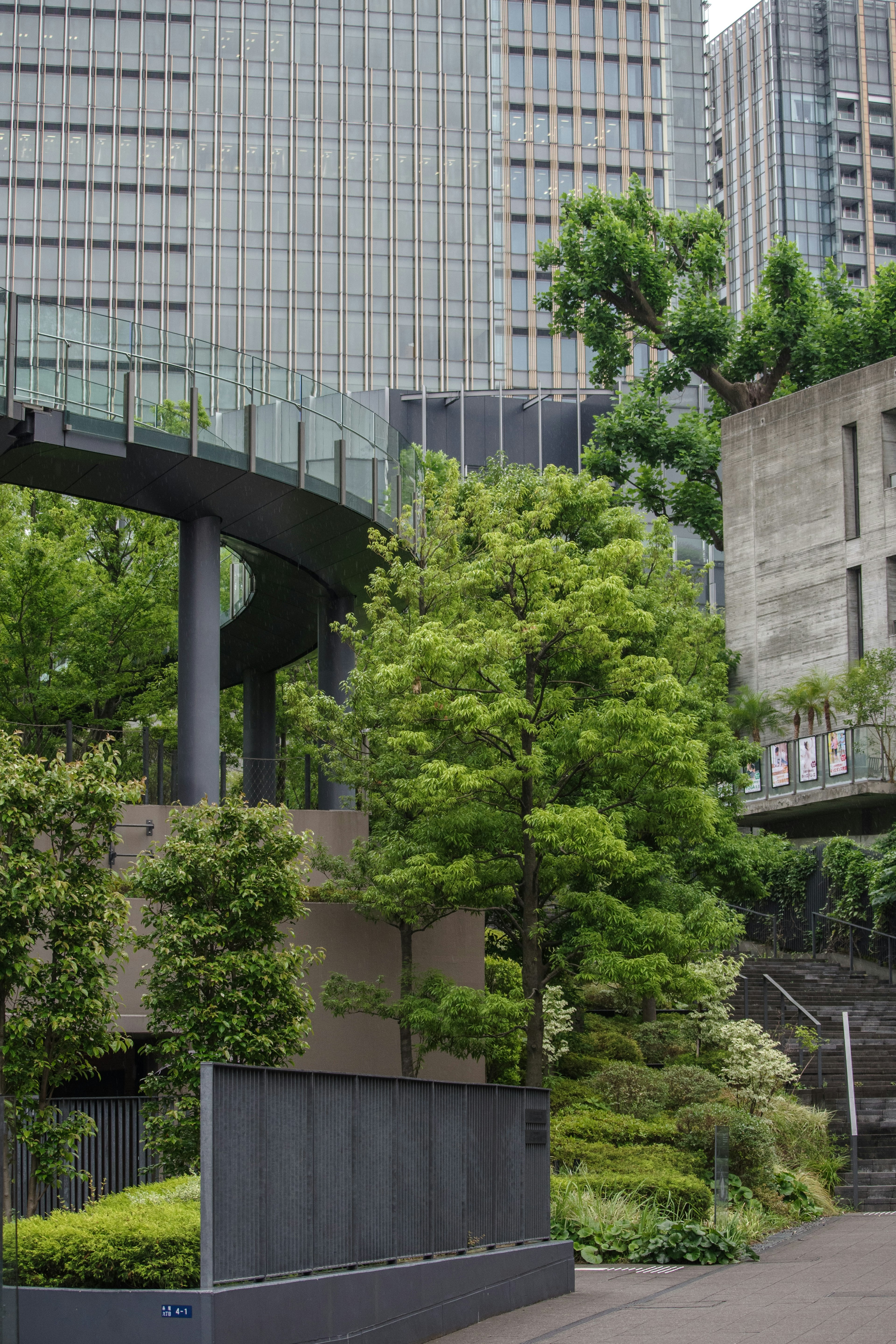 Urban landscape featuring lush greenery and a curved walkway against tall buildings