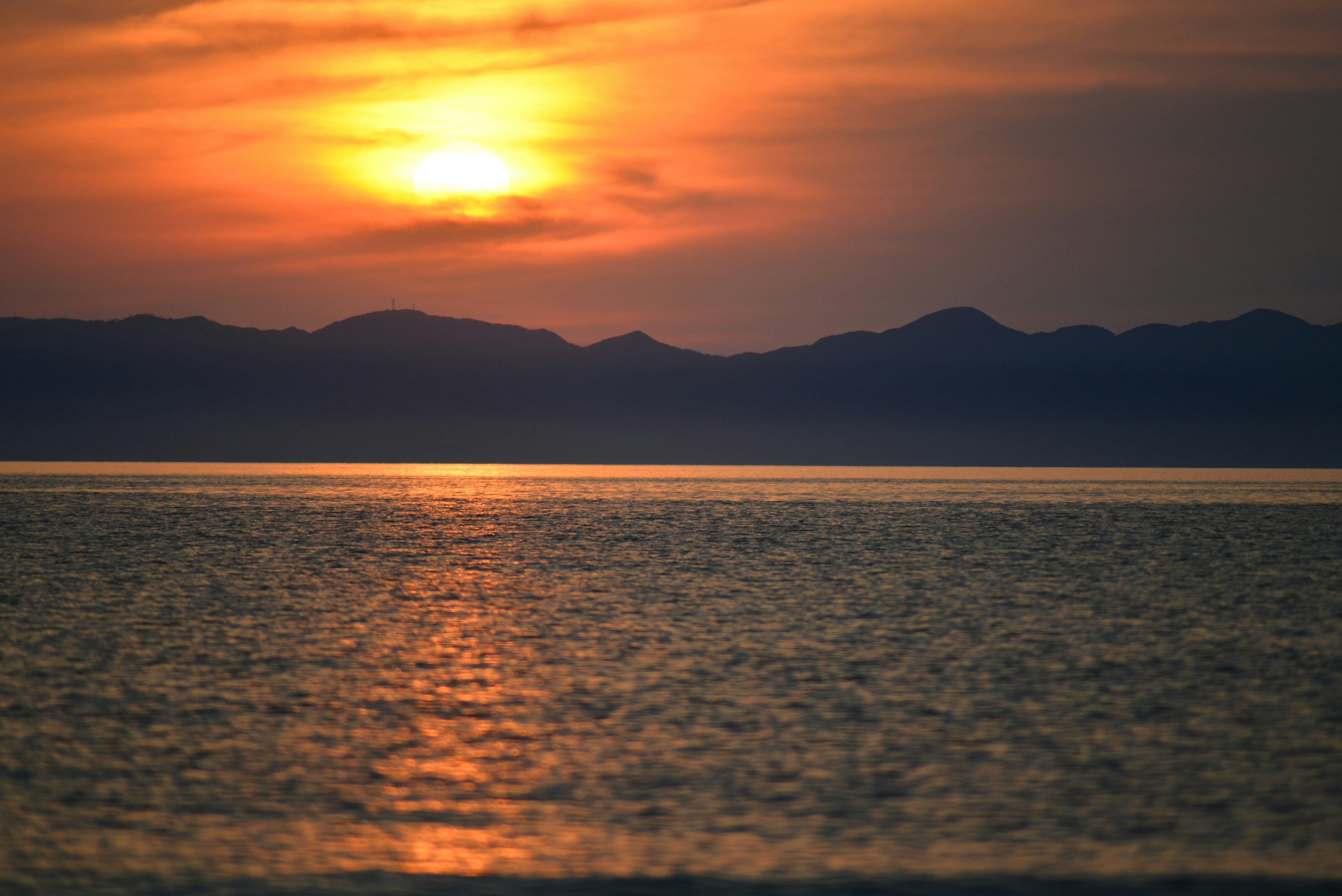 Schöner Sonnenuntergang über dem Ozean mit Bergen im Hintergrund