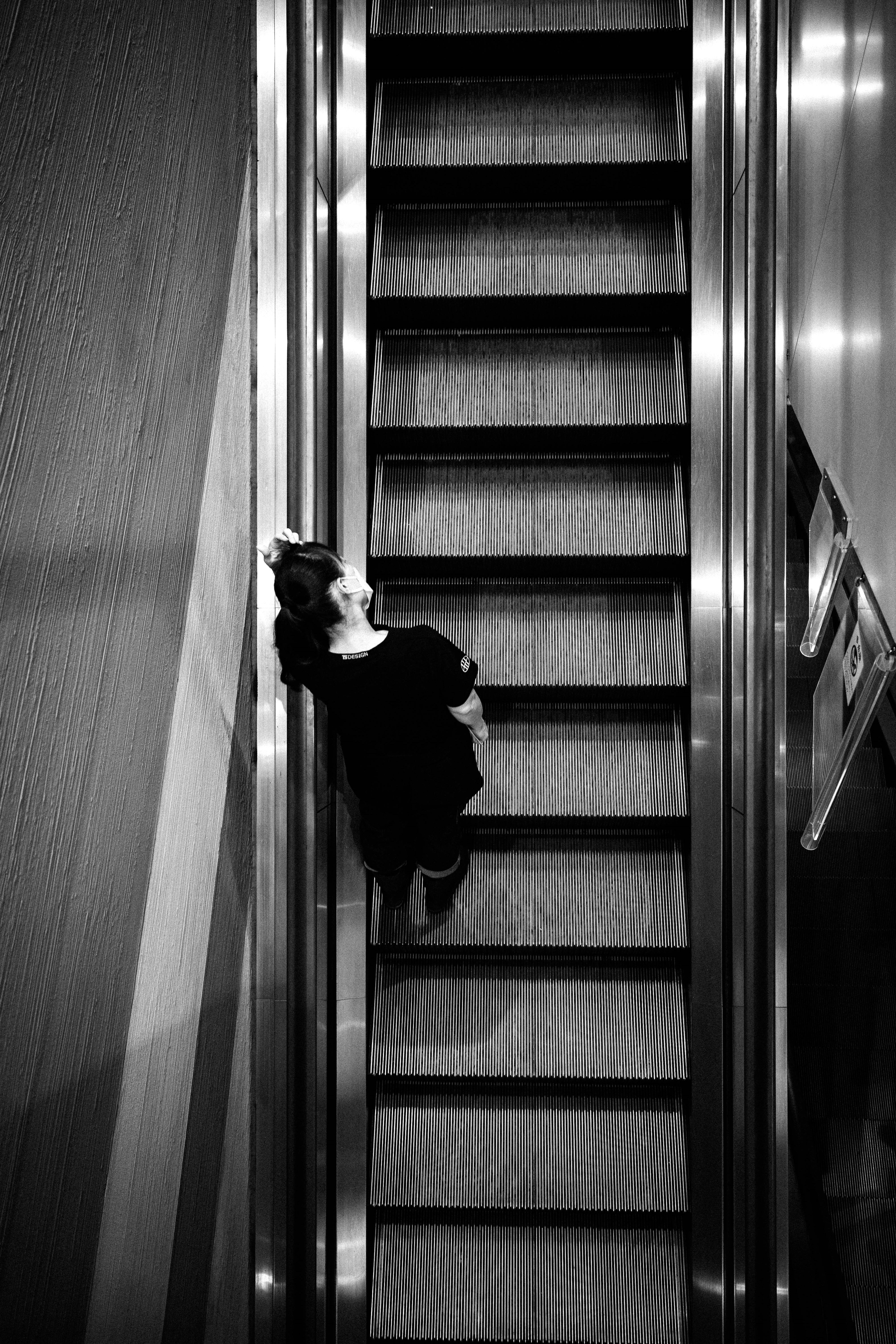 Black and white photo of a woman on an escalator from above