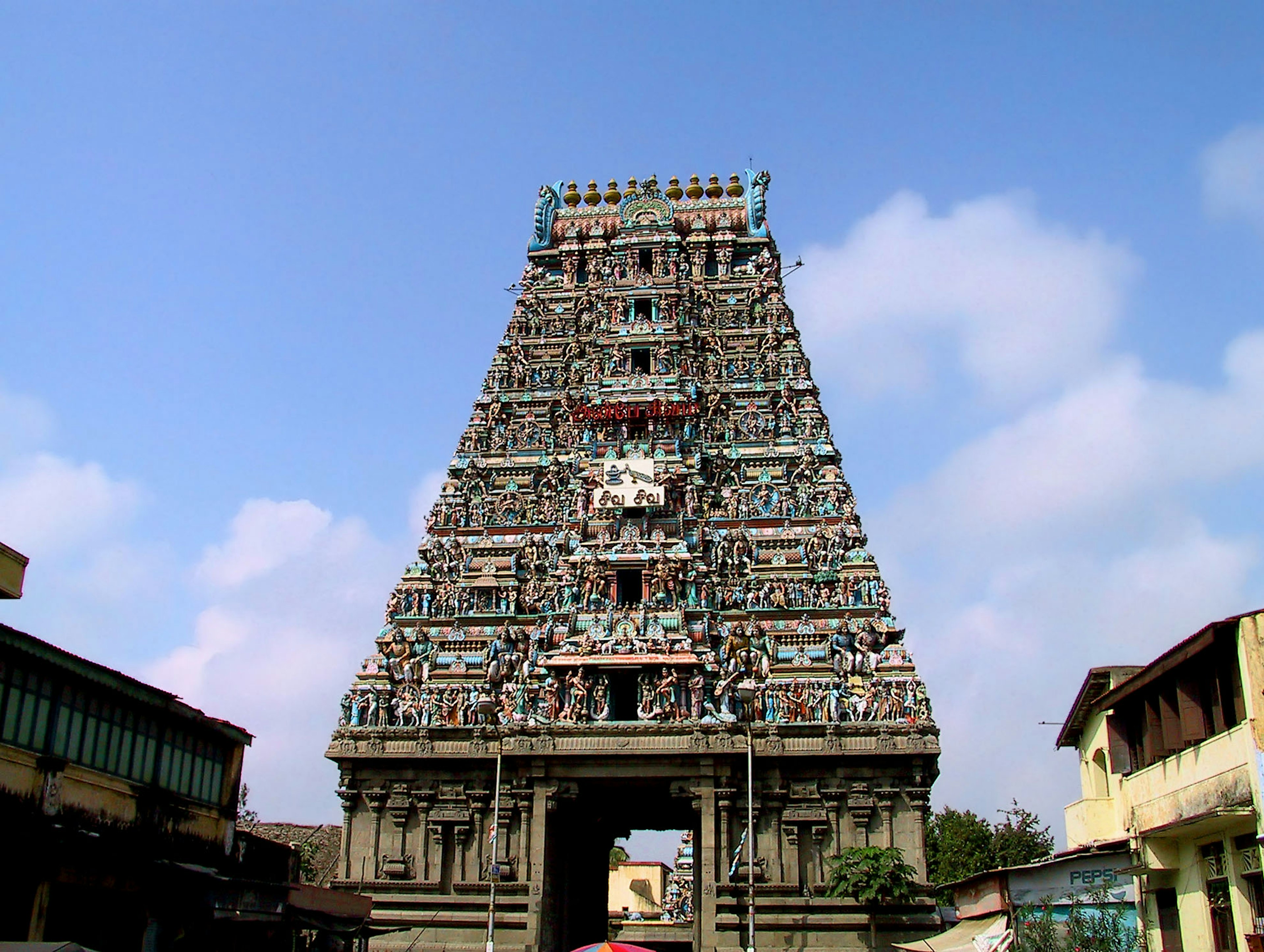 South Indian temple tower adorned with colorful sculptures against a bright blue sky