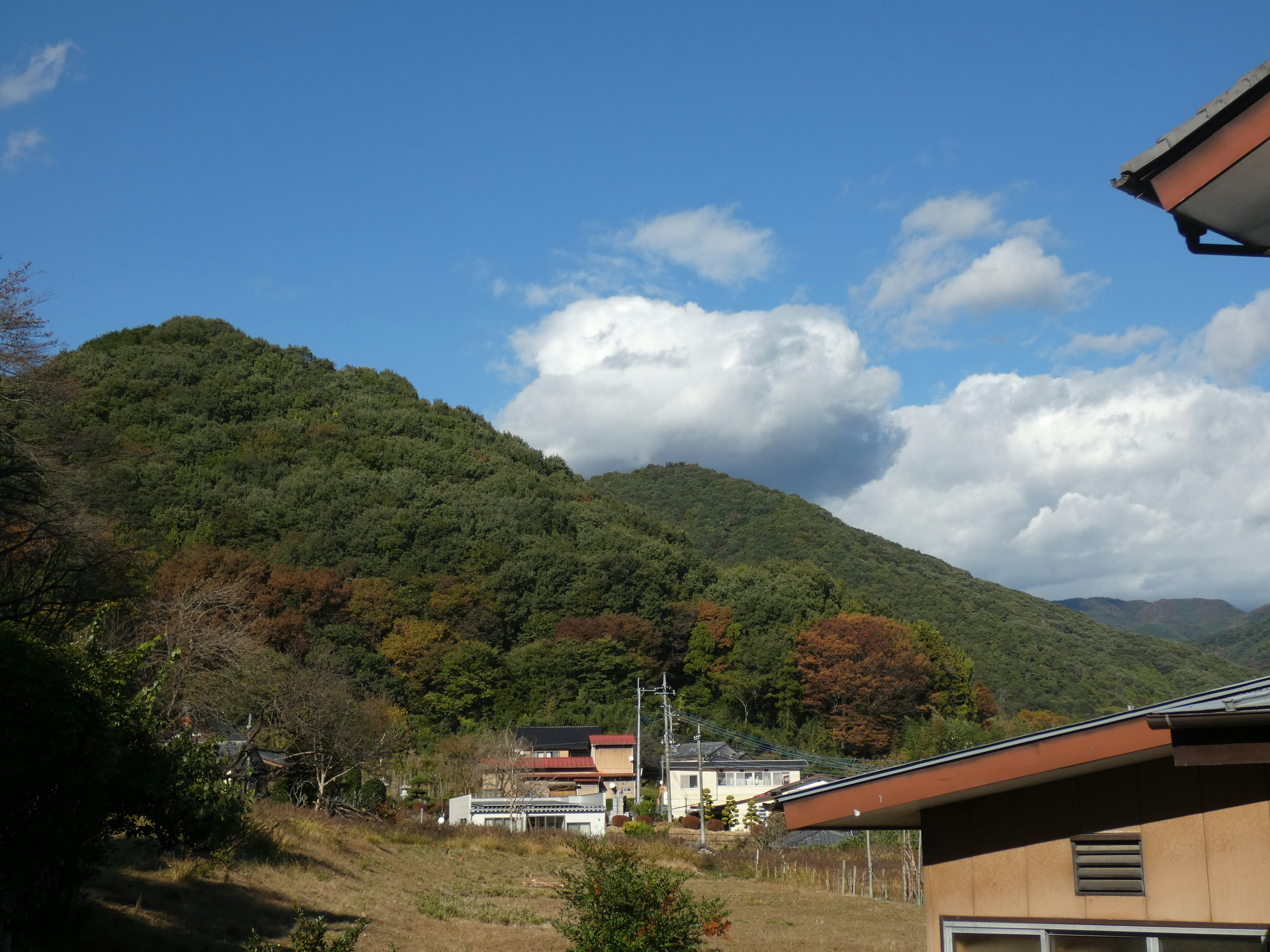 蓝天和白云的山景 绿色山丘和宁静村庄可见