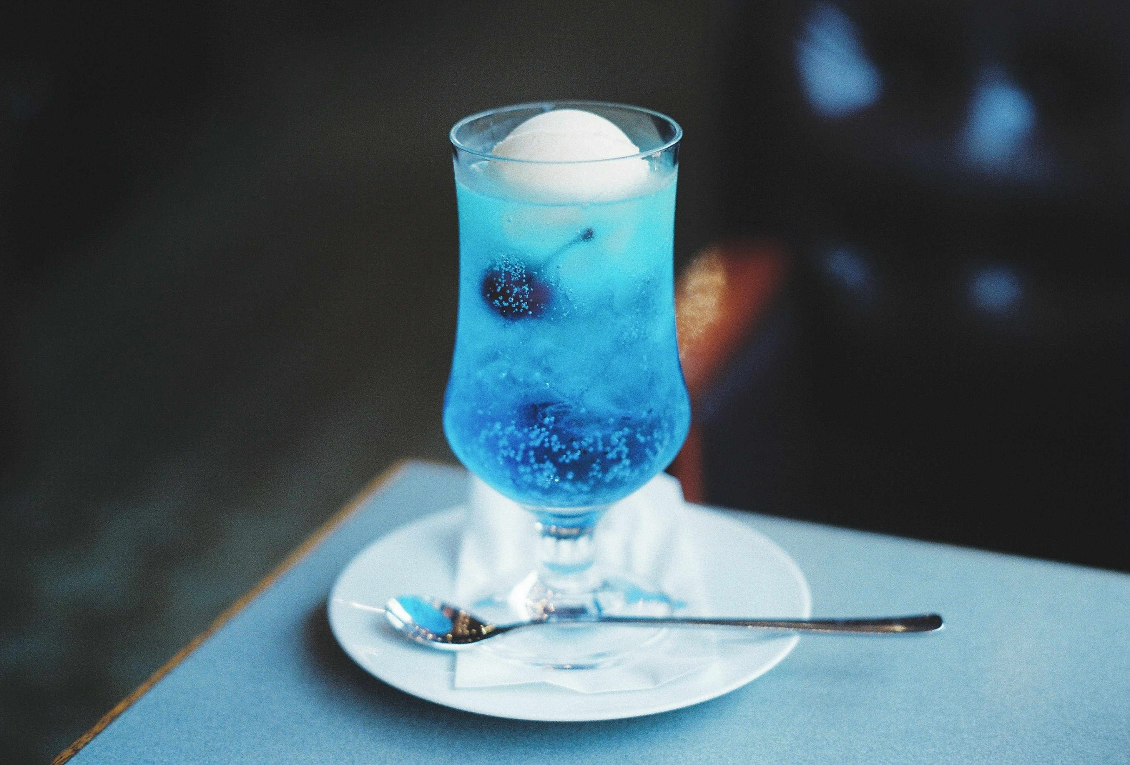 Cocktail glass with blue drink and ice cream on top