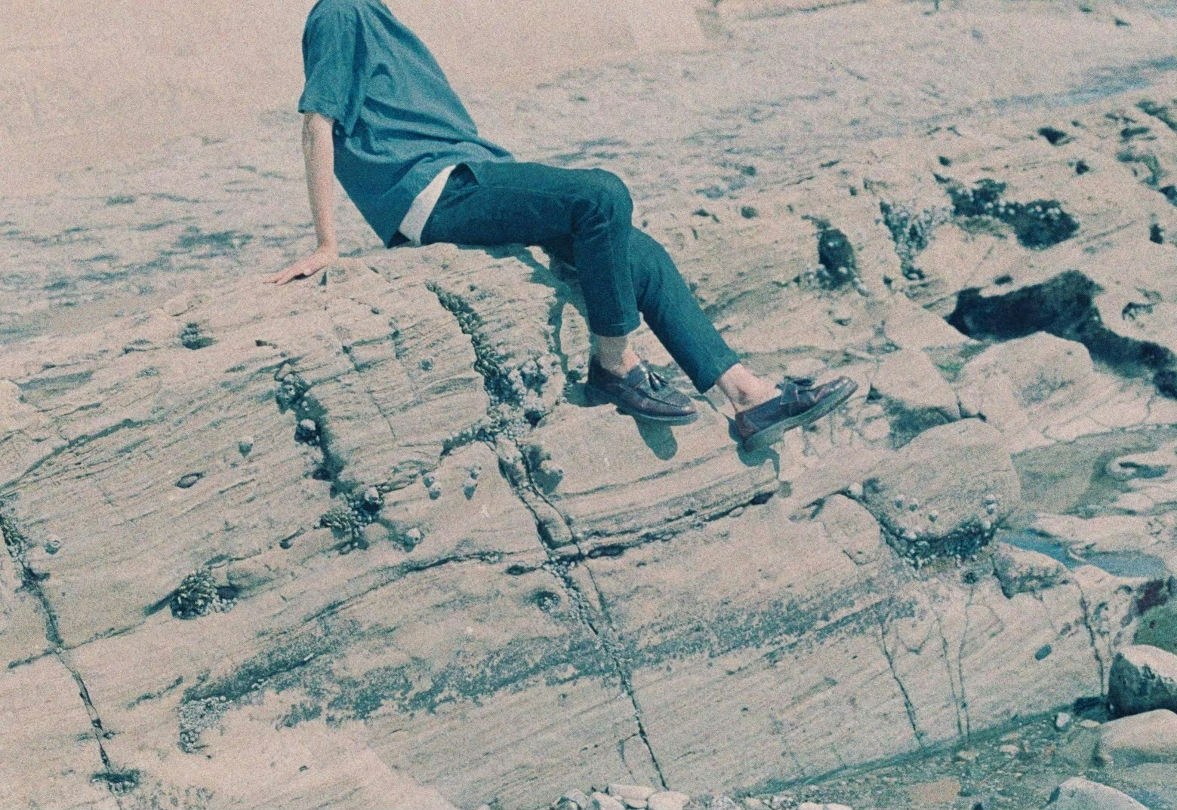 Person sitting on a rock wearing a blue shirt natural scenery