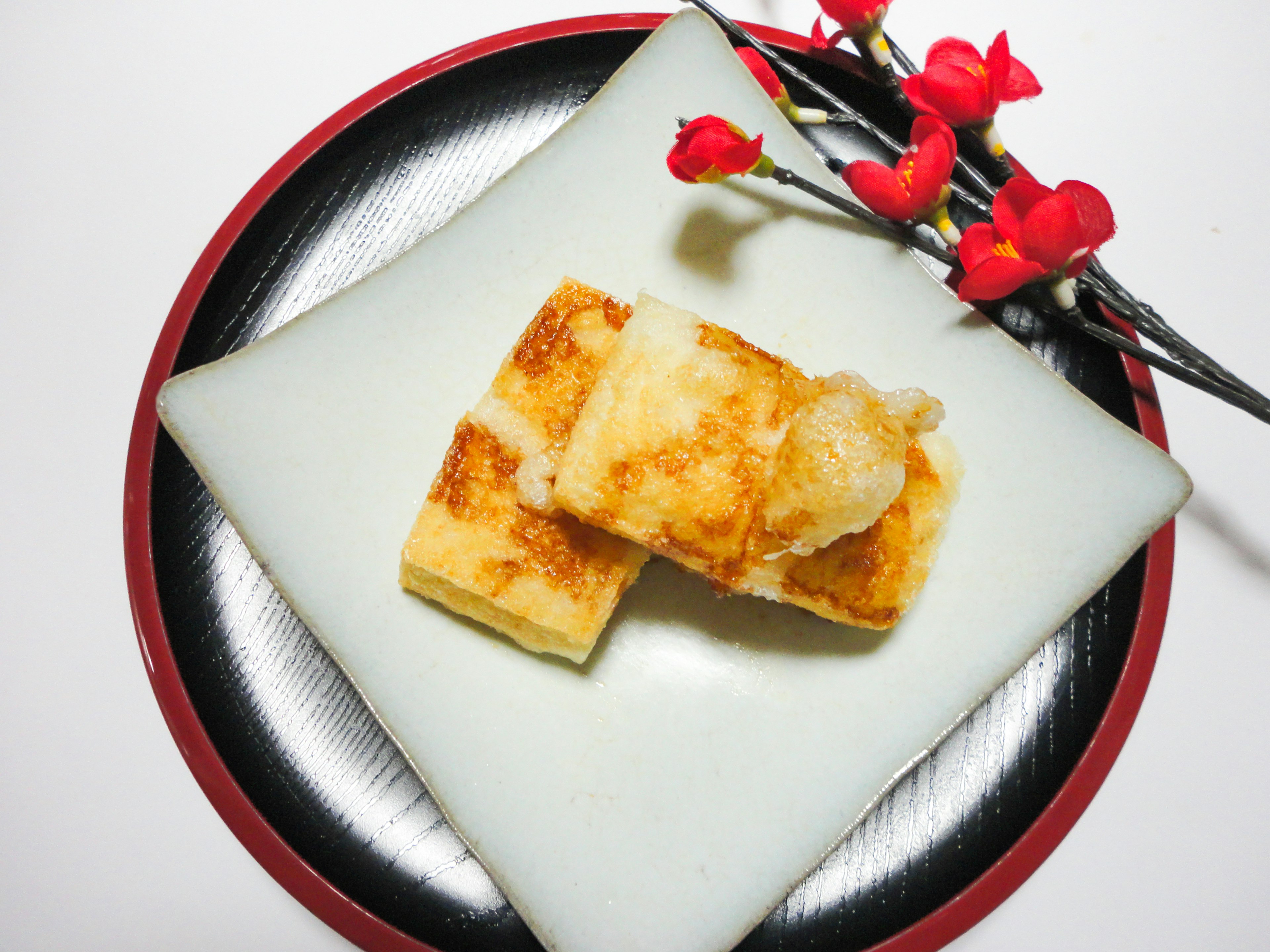 Grilled tofu served on a white plate with decorative red flowers