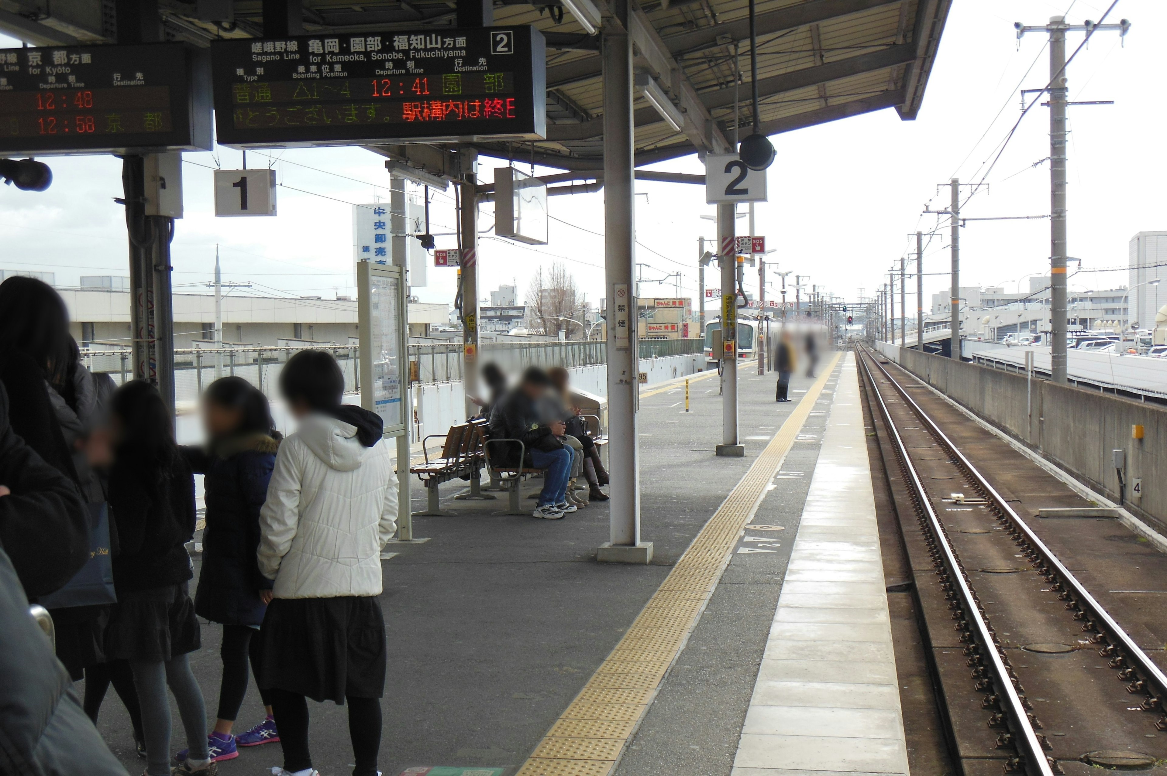 People at a train station platform with visible railway tracks