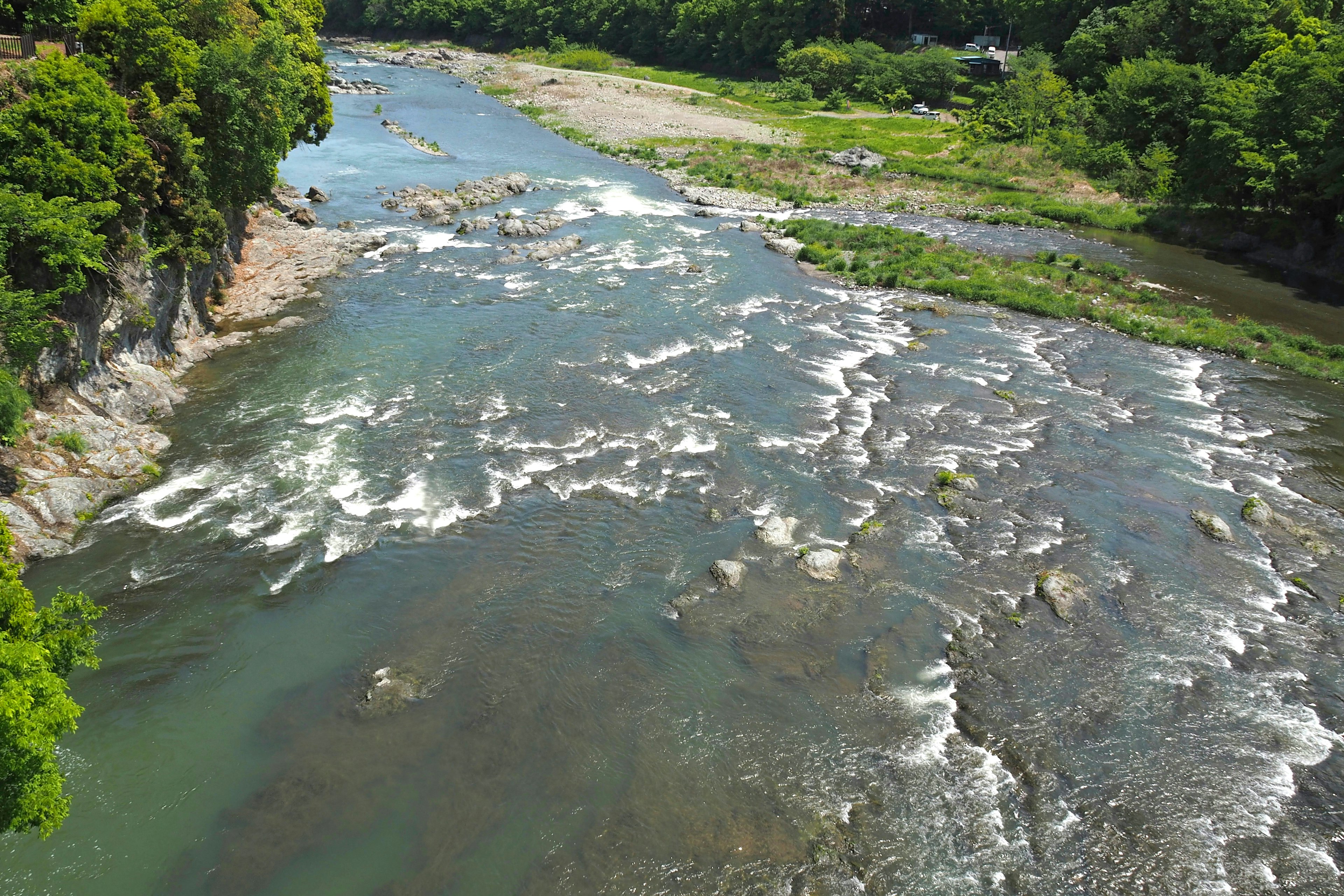 Ruhiger Fluss, der durch üppiges Grün mit felsigen Ufern fließt