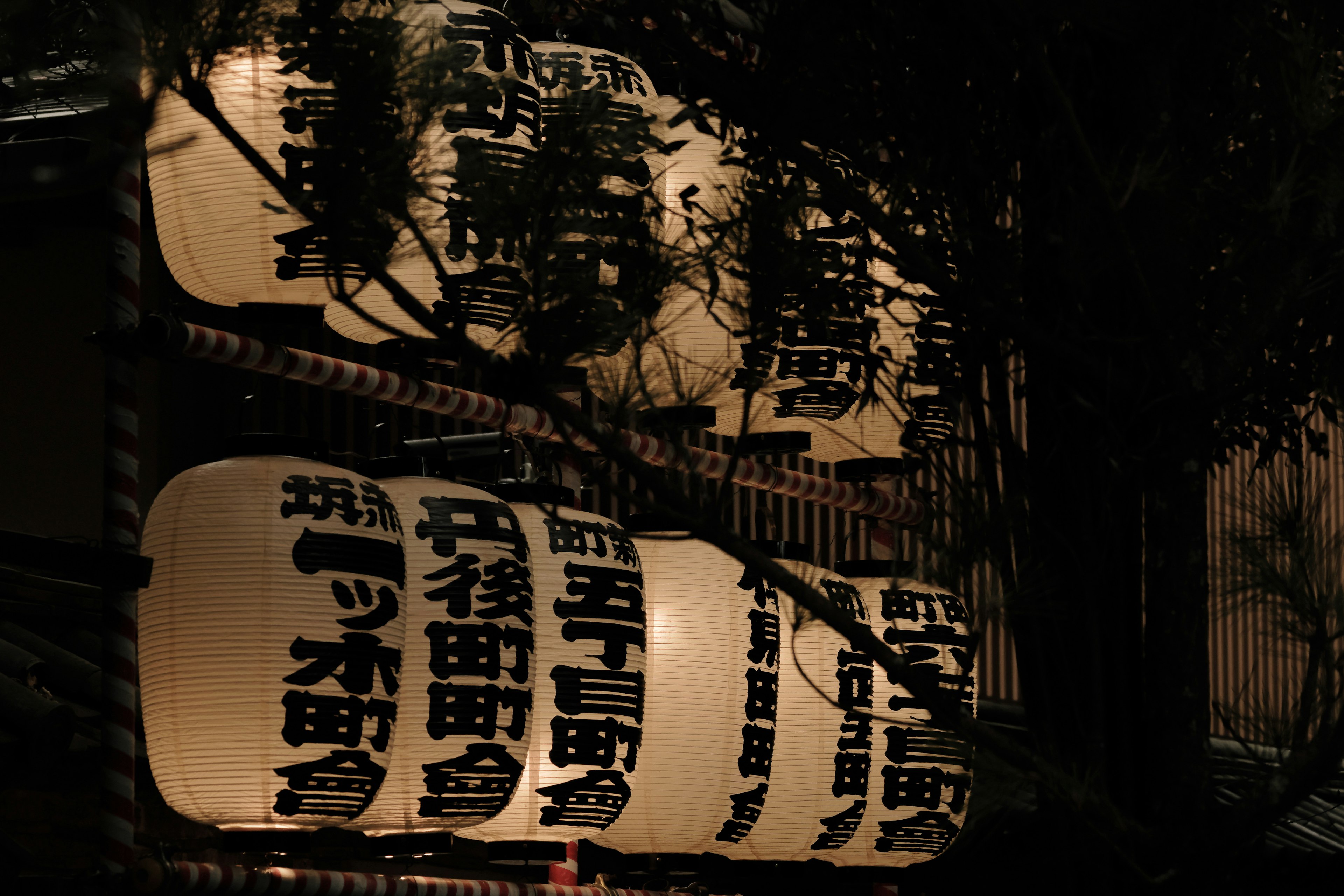 Japanese street lantern sign illuminated against a dark background displaying kanji place names