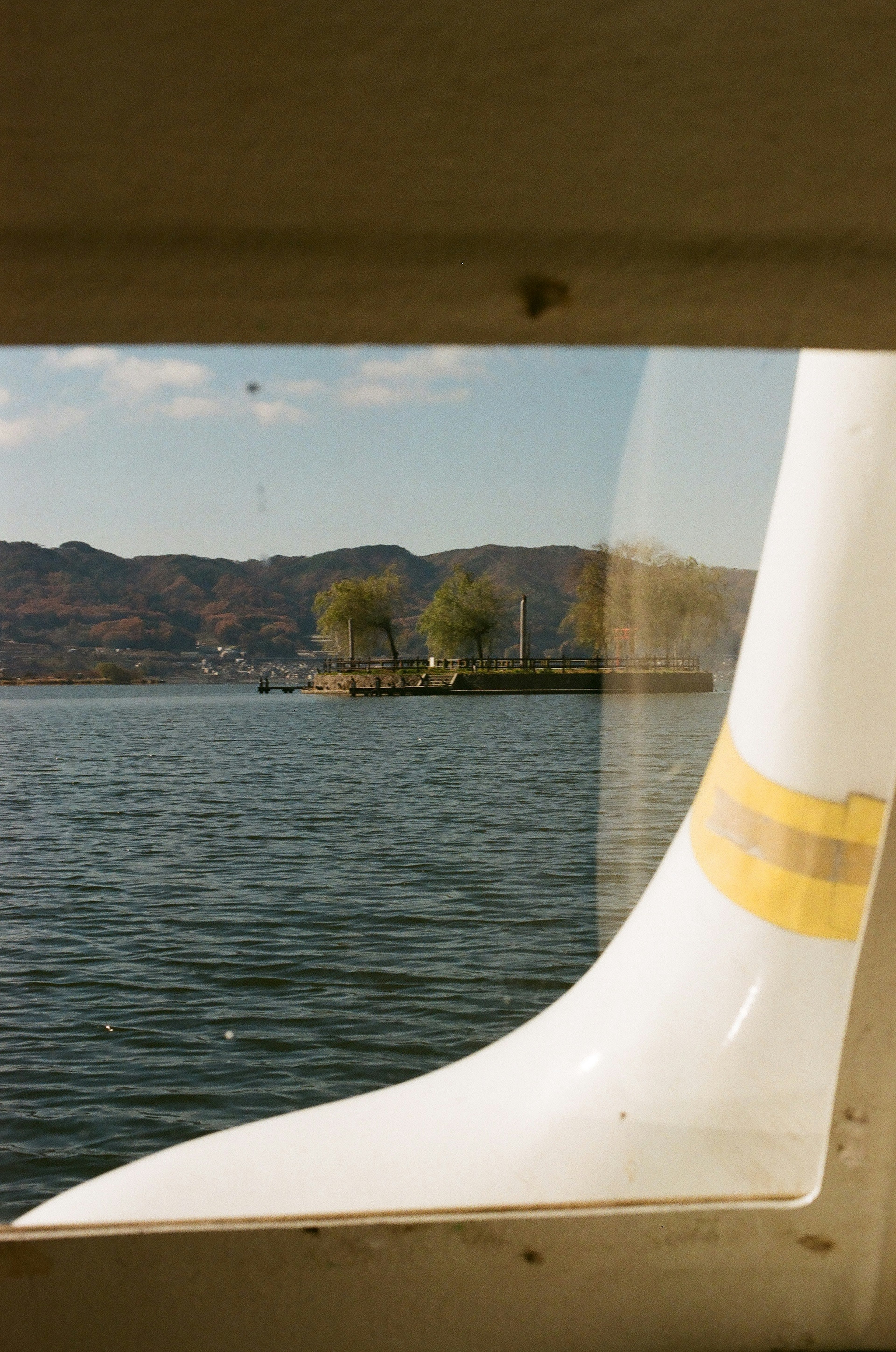 Vista de un lago y una isla a través de una ventana con una hélice en primer plano