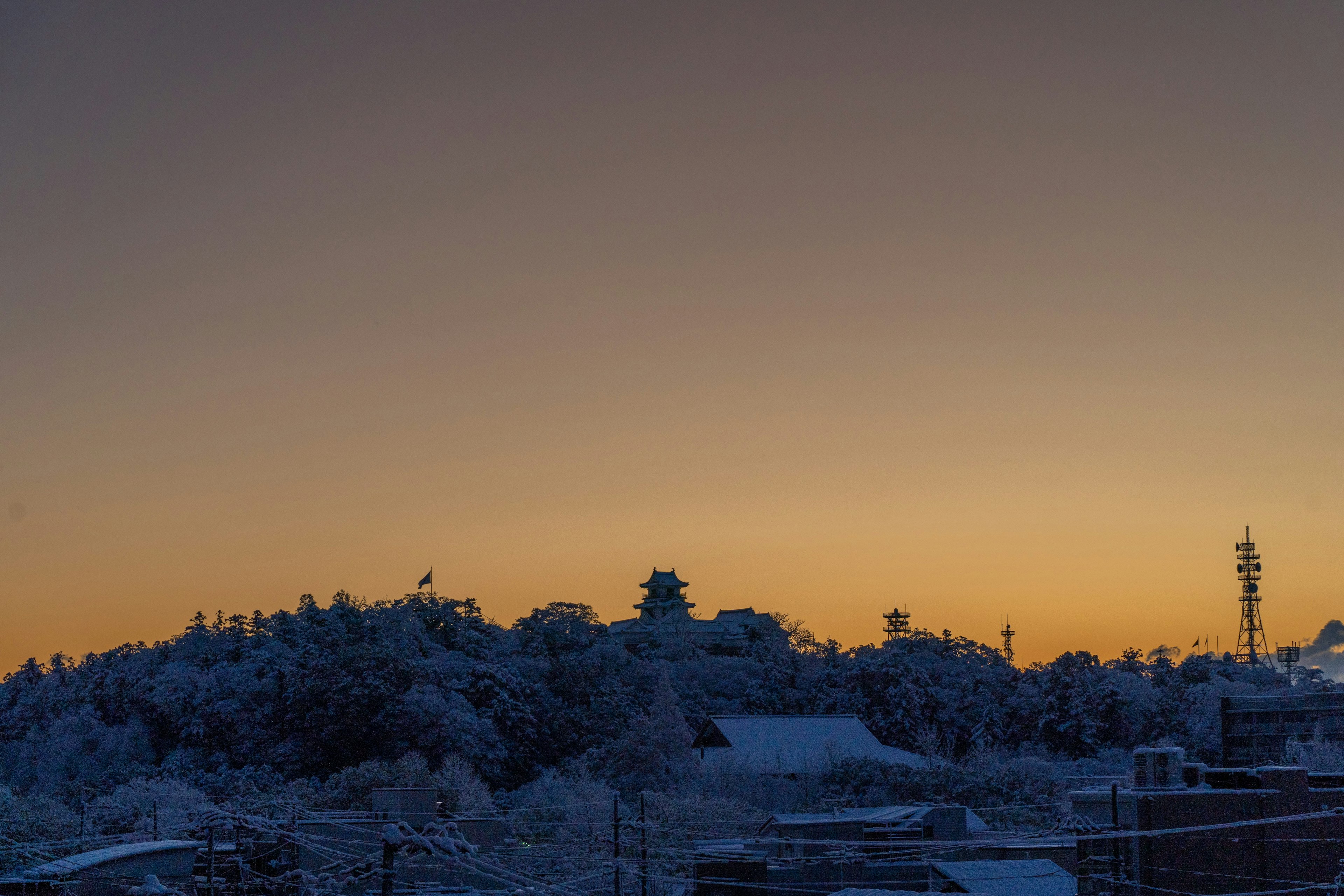 被雪覆蓋的山丘和美麗的橙色日落背景