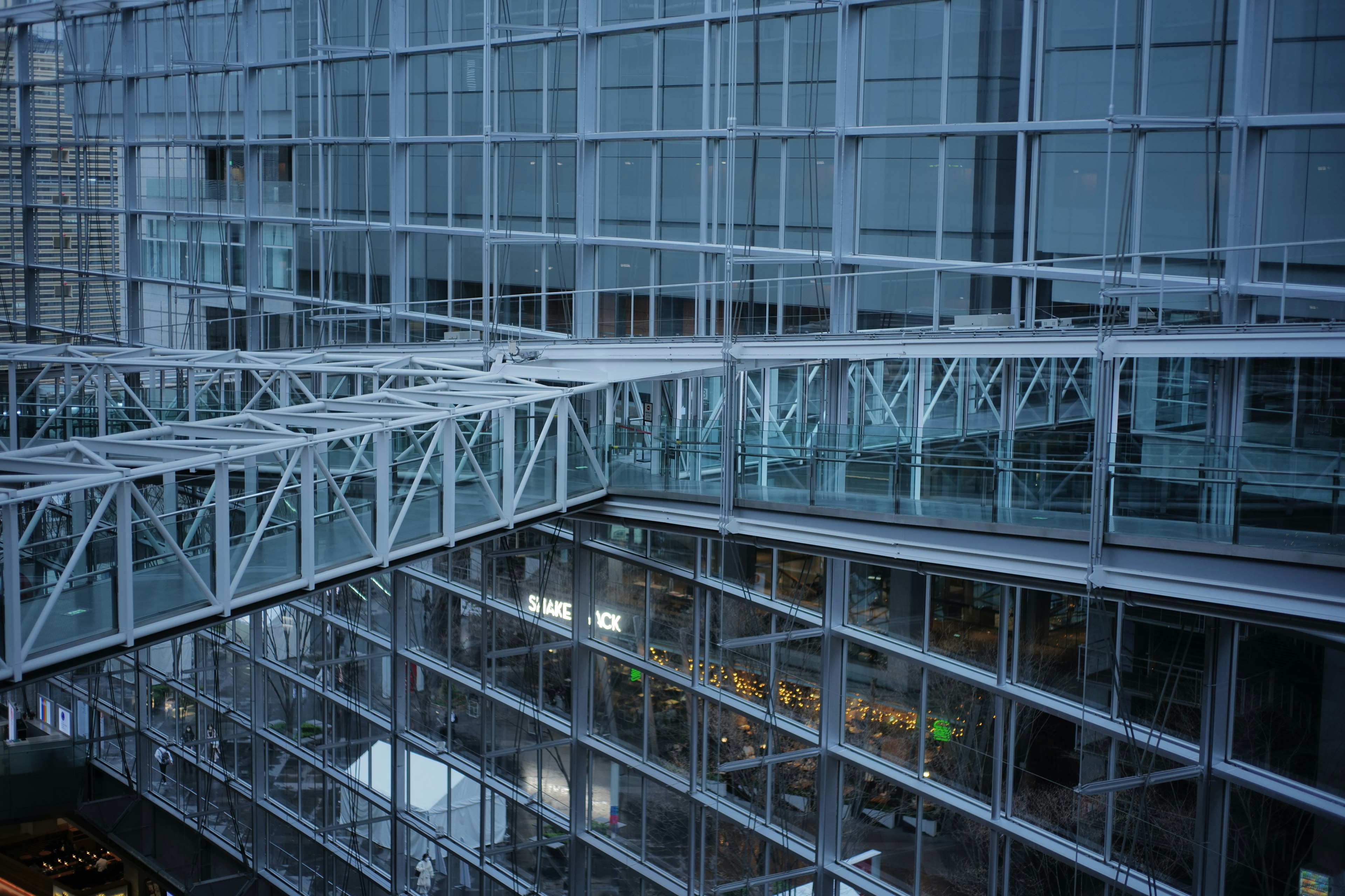 Edificio moderno con estructura de vidrio y metal que presenta un puente interno