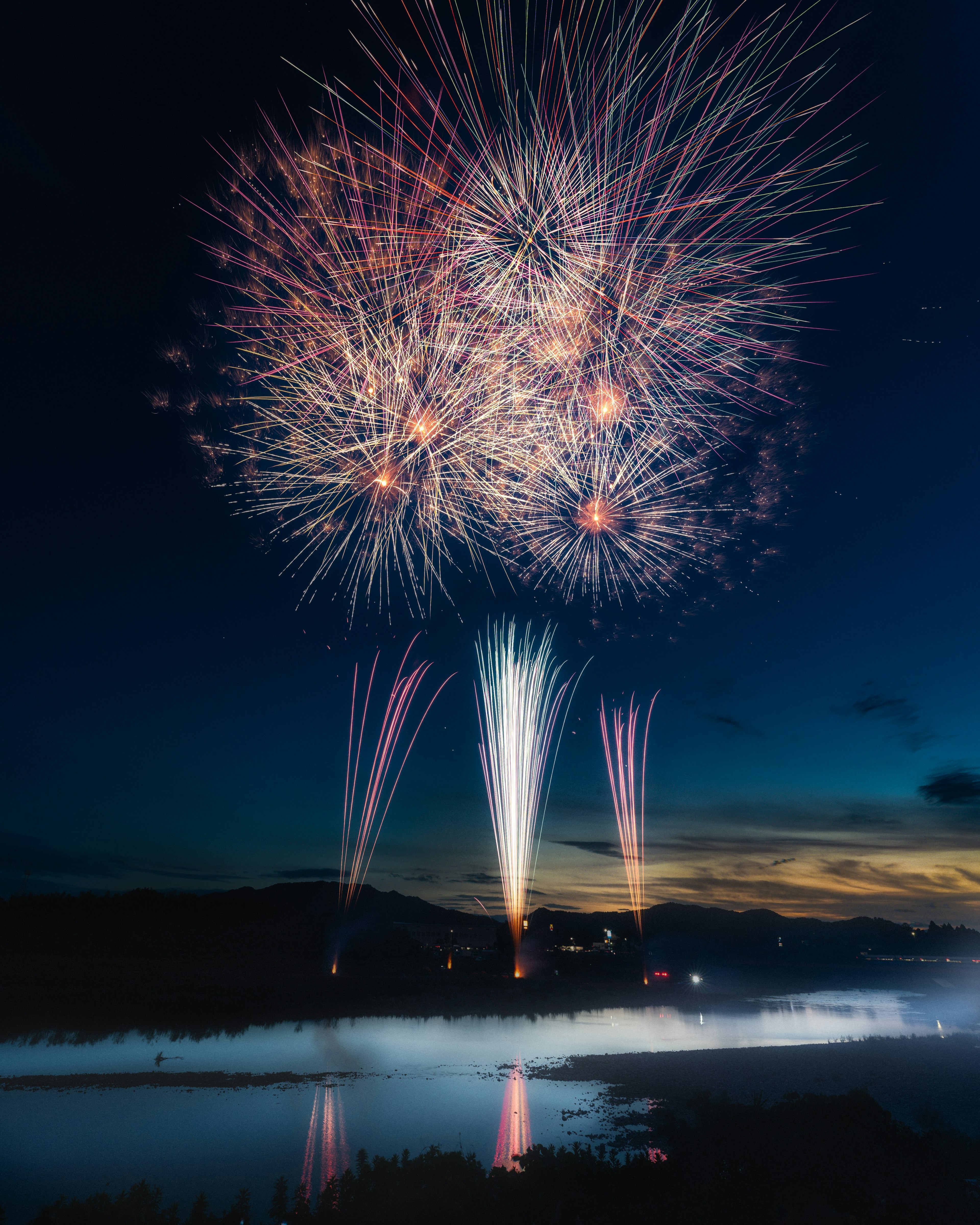 Spettacolo di fuochi d'artificio che illumina il cielo notturno riflessi sull'acqua