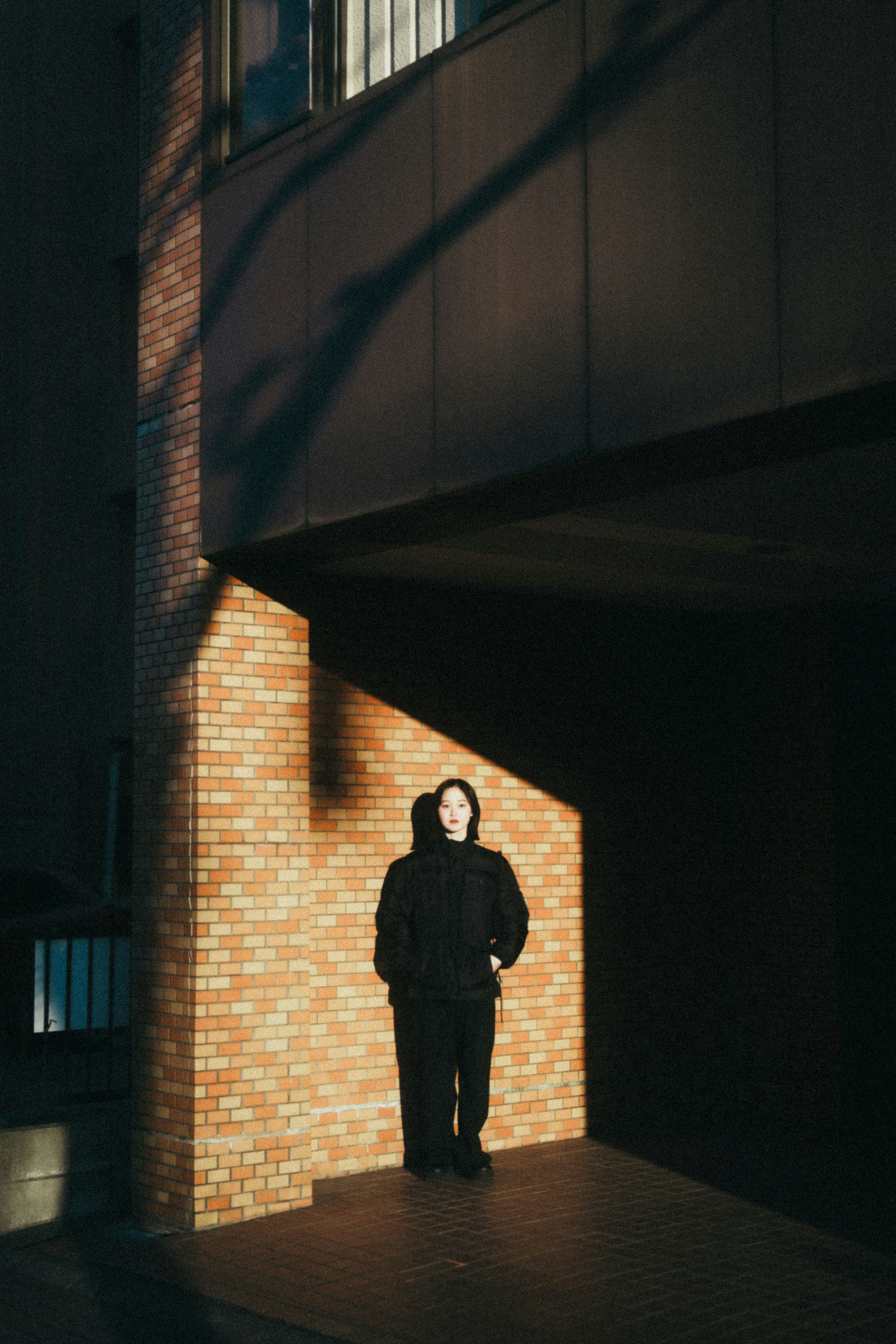 Une personne se tenant devant un bâtiment avec des ombres et de la lumière contrastées