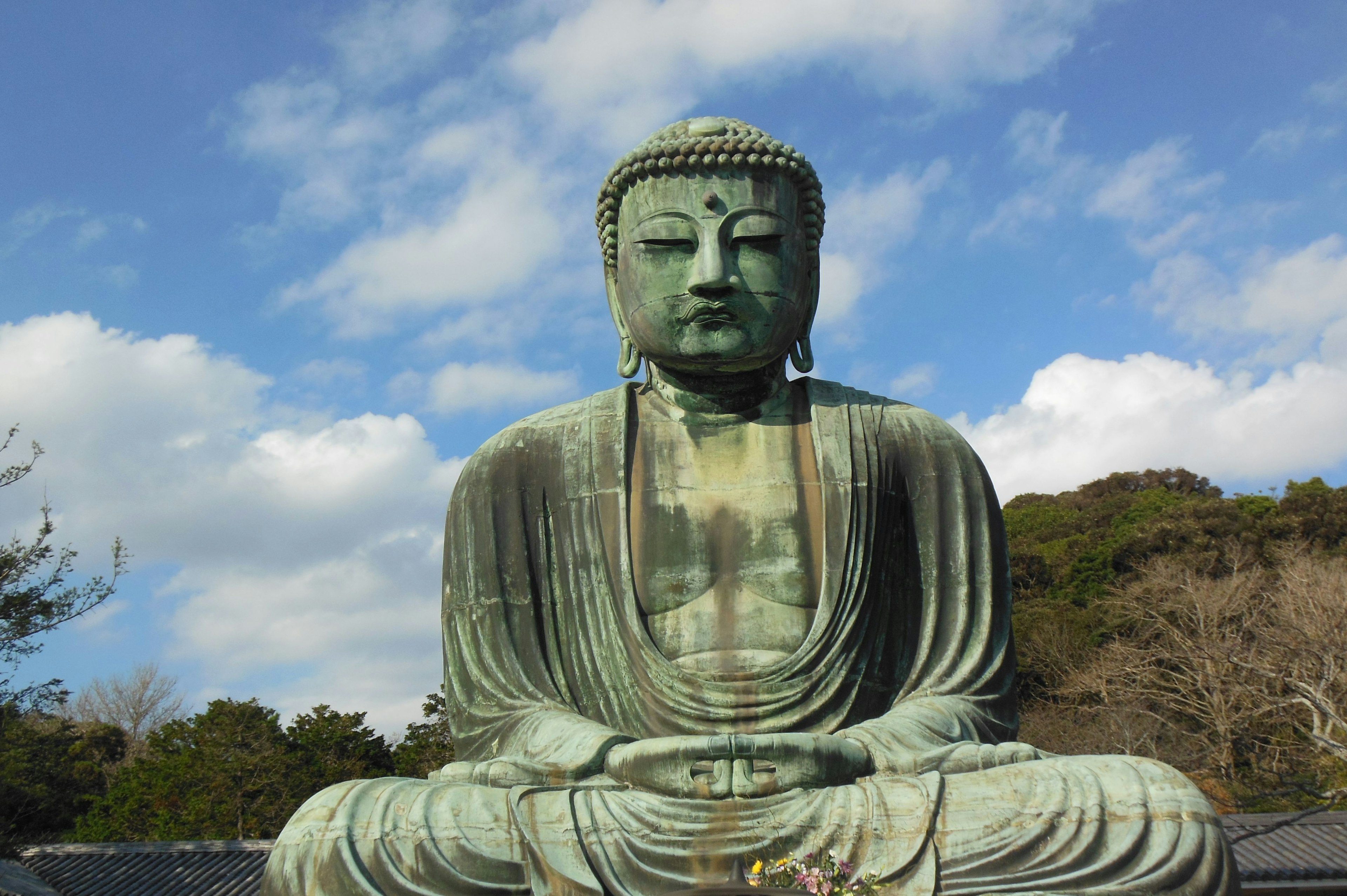 Bronze Buddha statue seated against a backdrop of blue sky and clouds