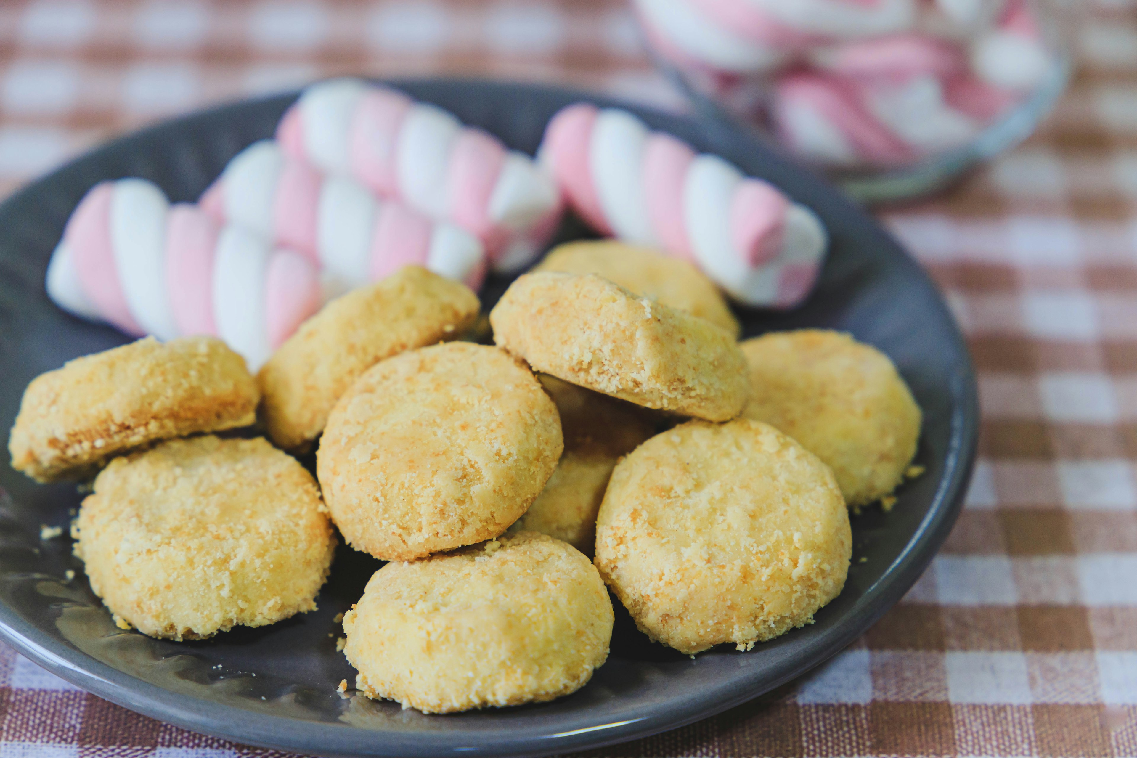 Piring berisi kue kuning dengan marshmallow bergaris di latar belakang