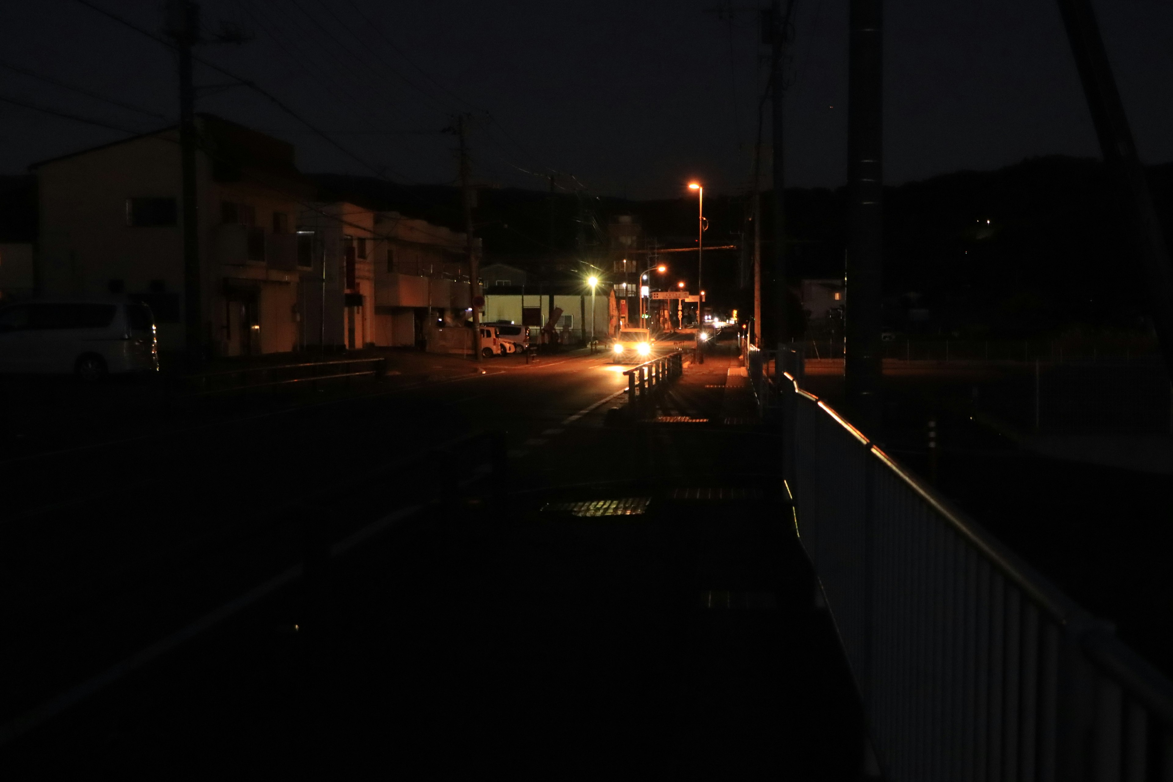 Escena de calle por la noche con farolas y faros de coche