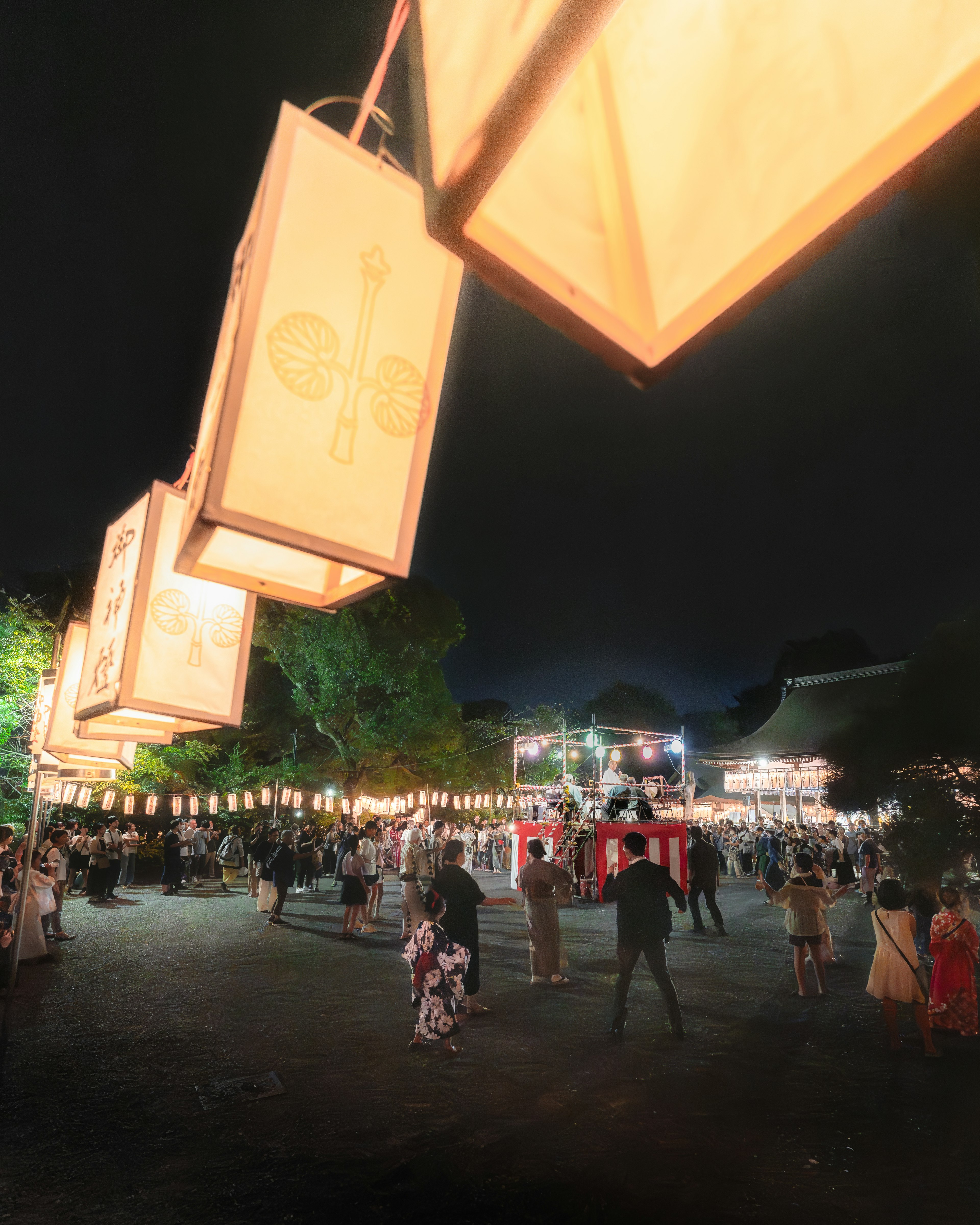 Festival at night with hanging lanterns and crowds of people