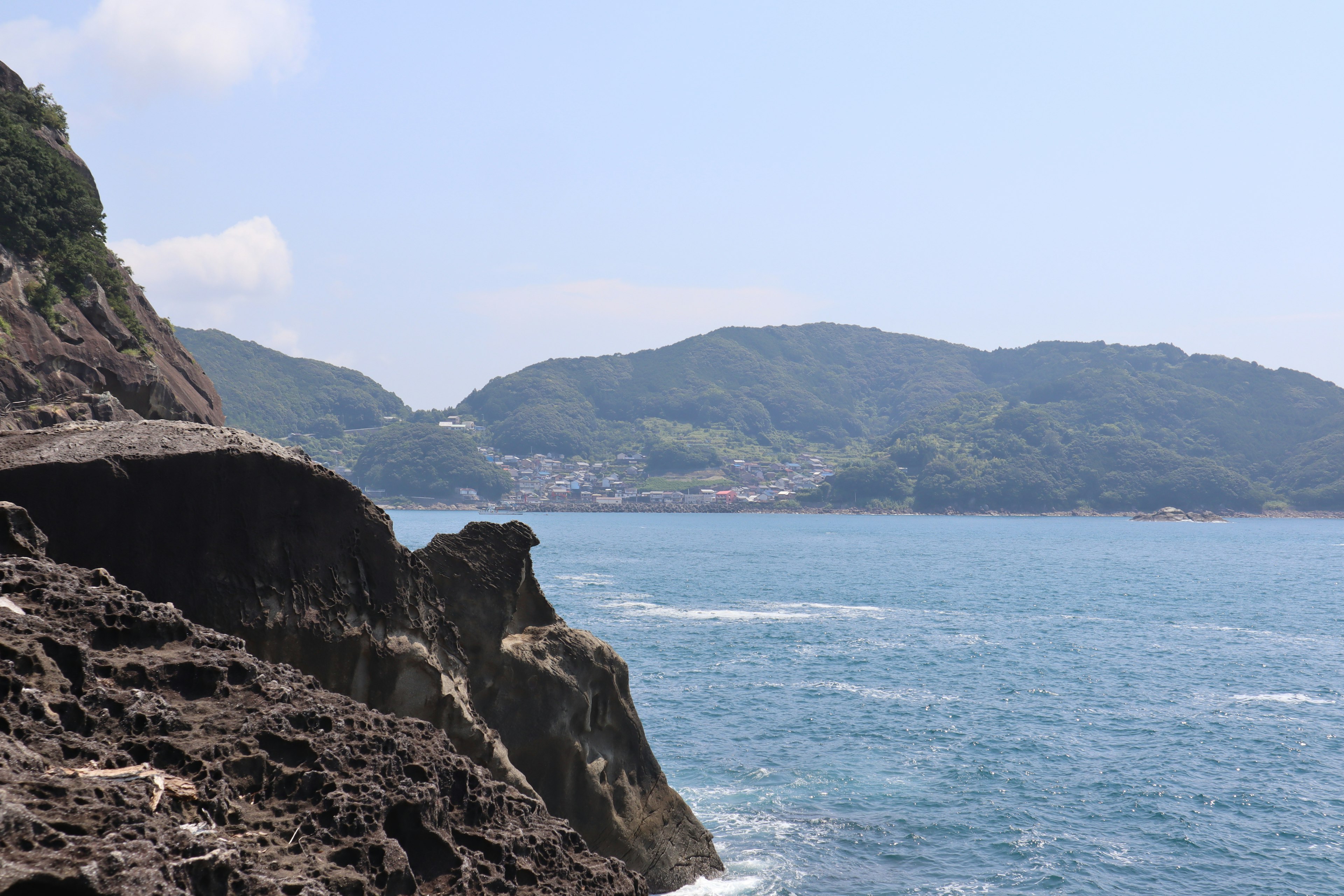 藍色海洋和綠色山脈的風景 岩石海岸線