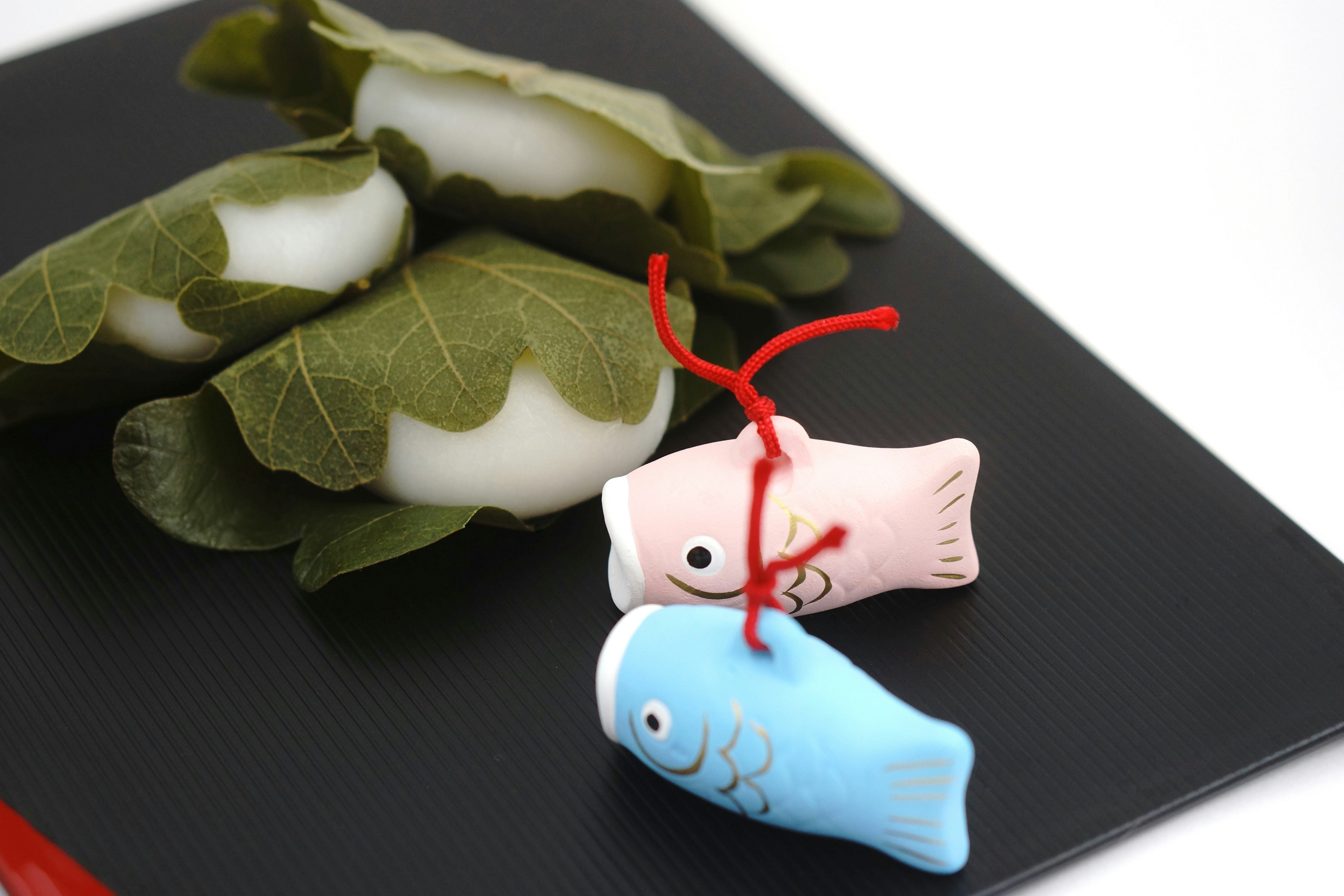 Japanese sweets wrapped in leaves with blue and pink fish decorations tied with red string