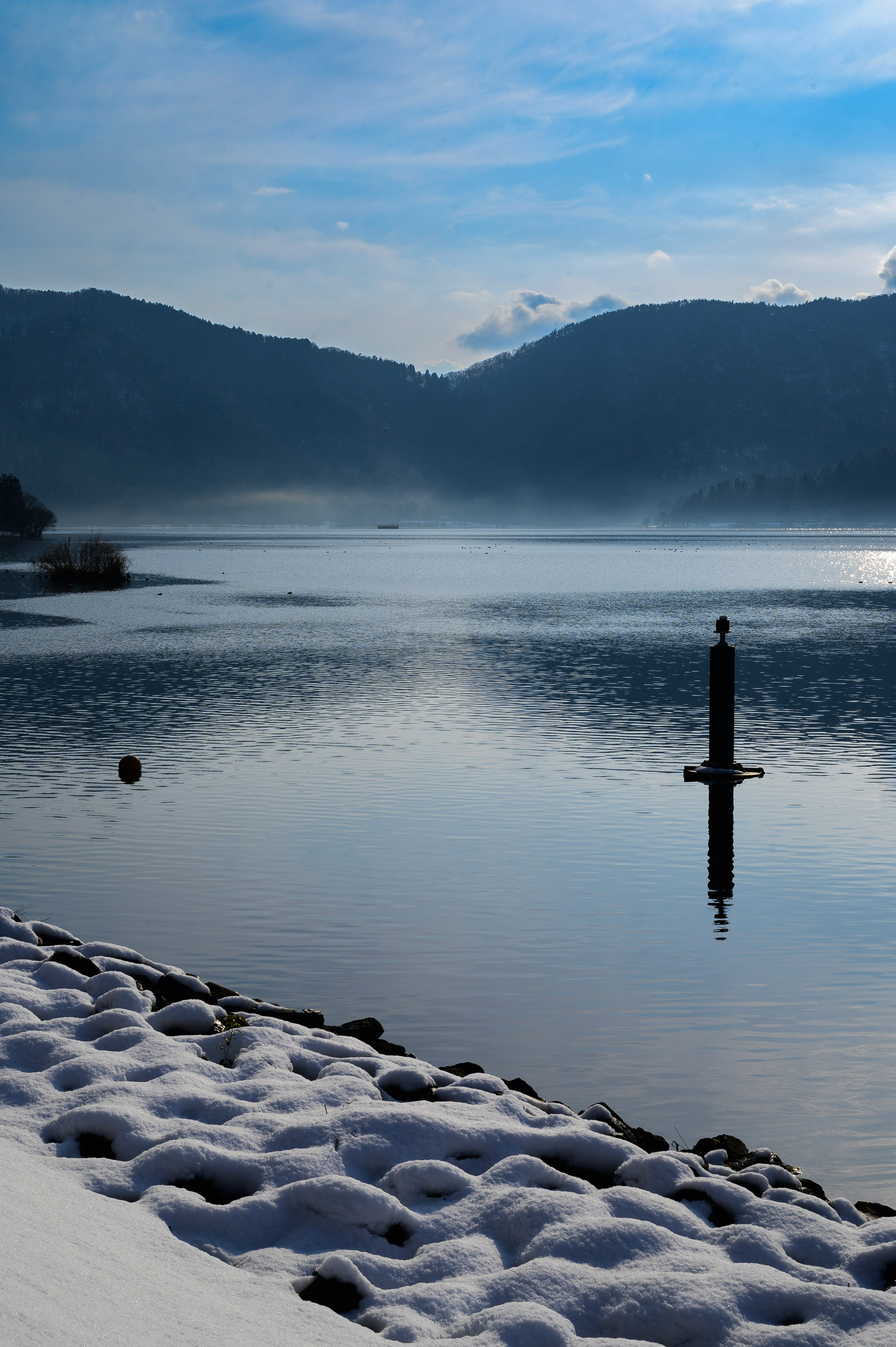 雪に覆われた岸辺と静かな湖の風景