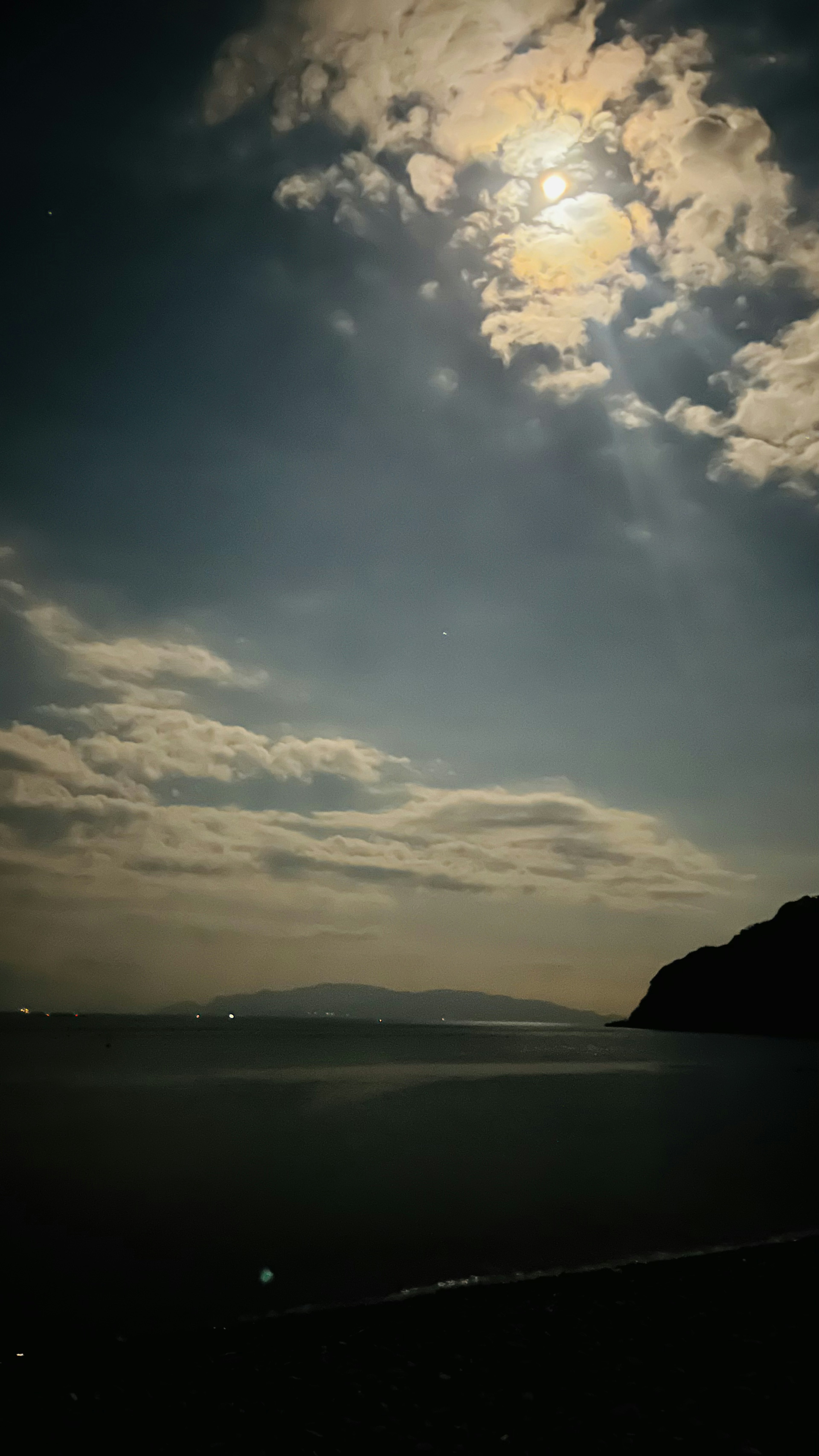 Dark sea with a cloudy sky and distant hills