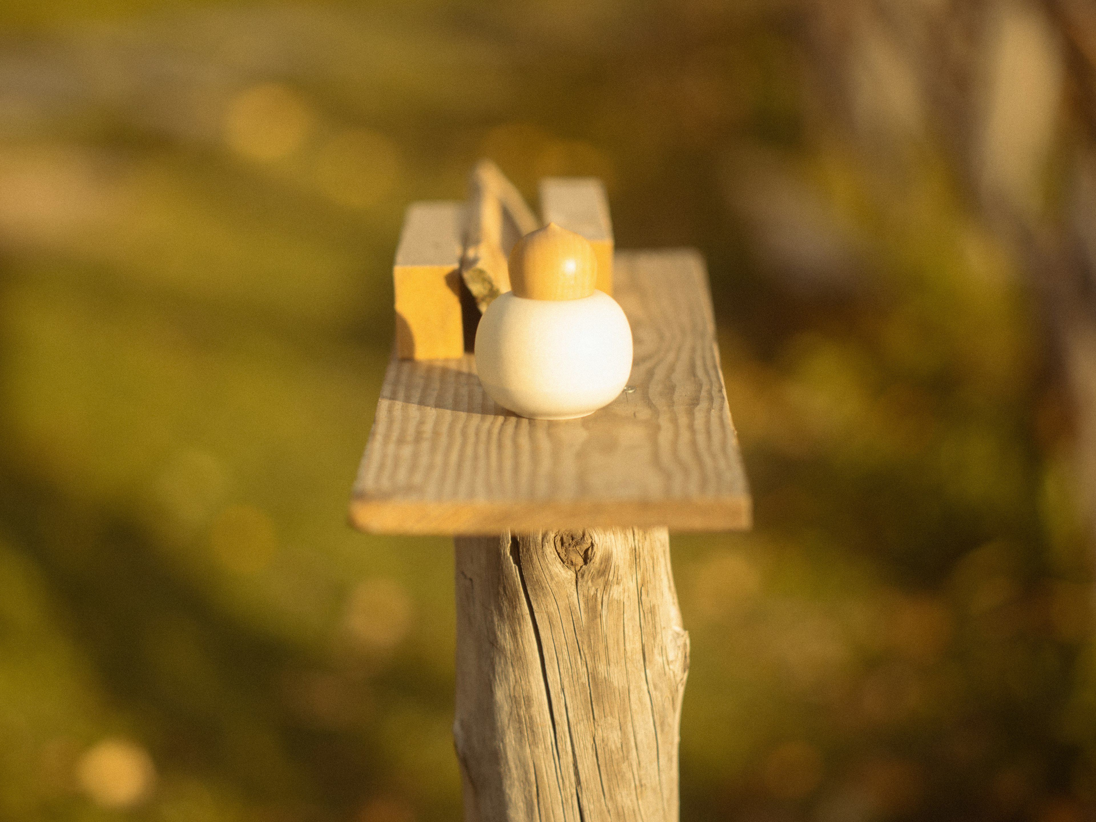 Un pot blanc et une petite boîte en bois sur une plateforme en bois