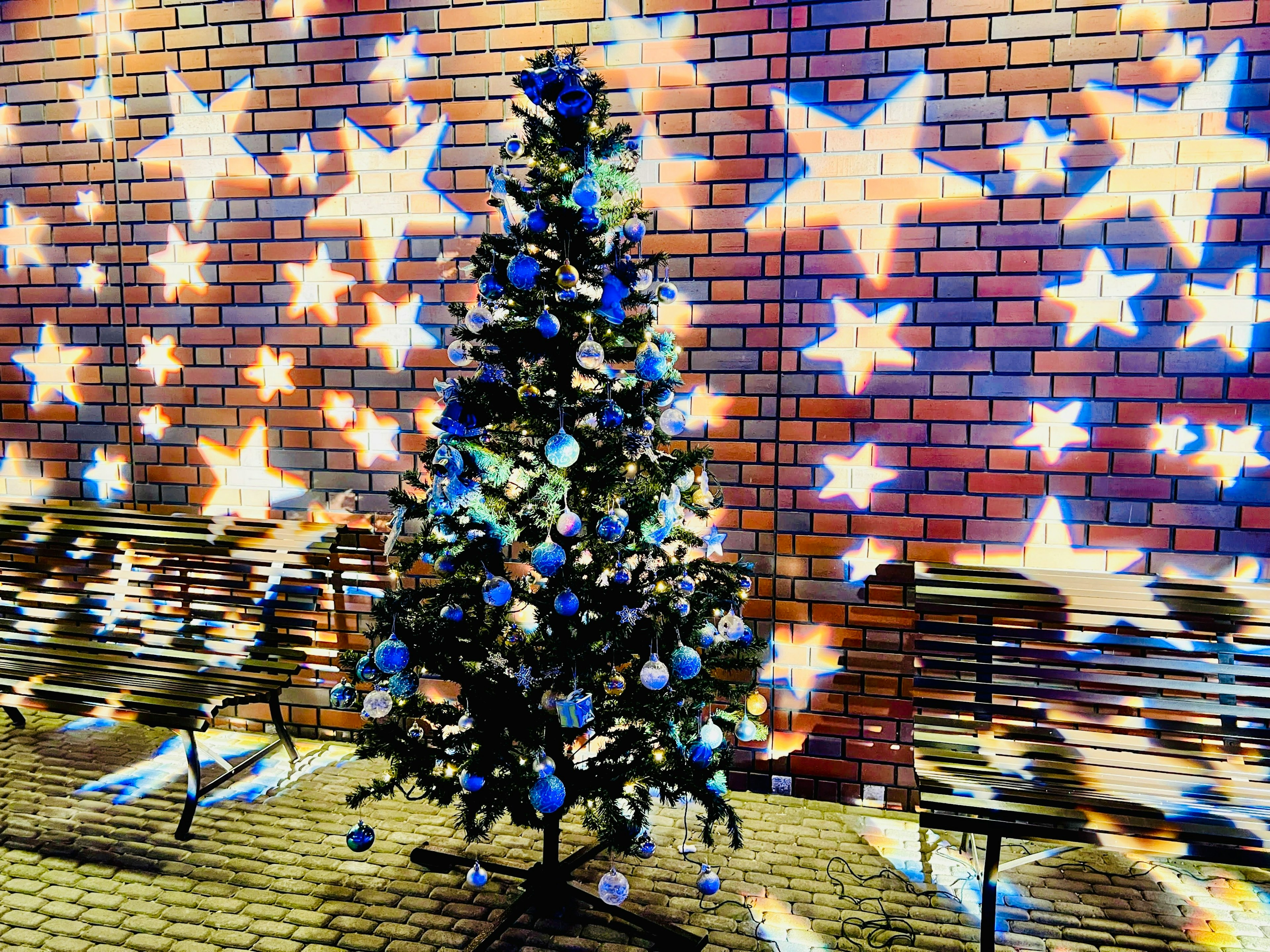 Christmas tree with blue and white decorations against a starry wall