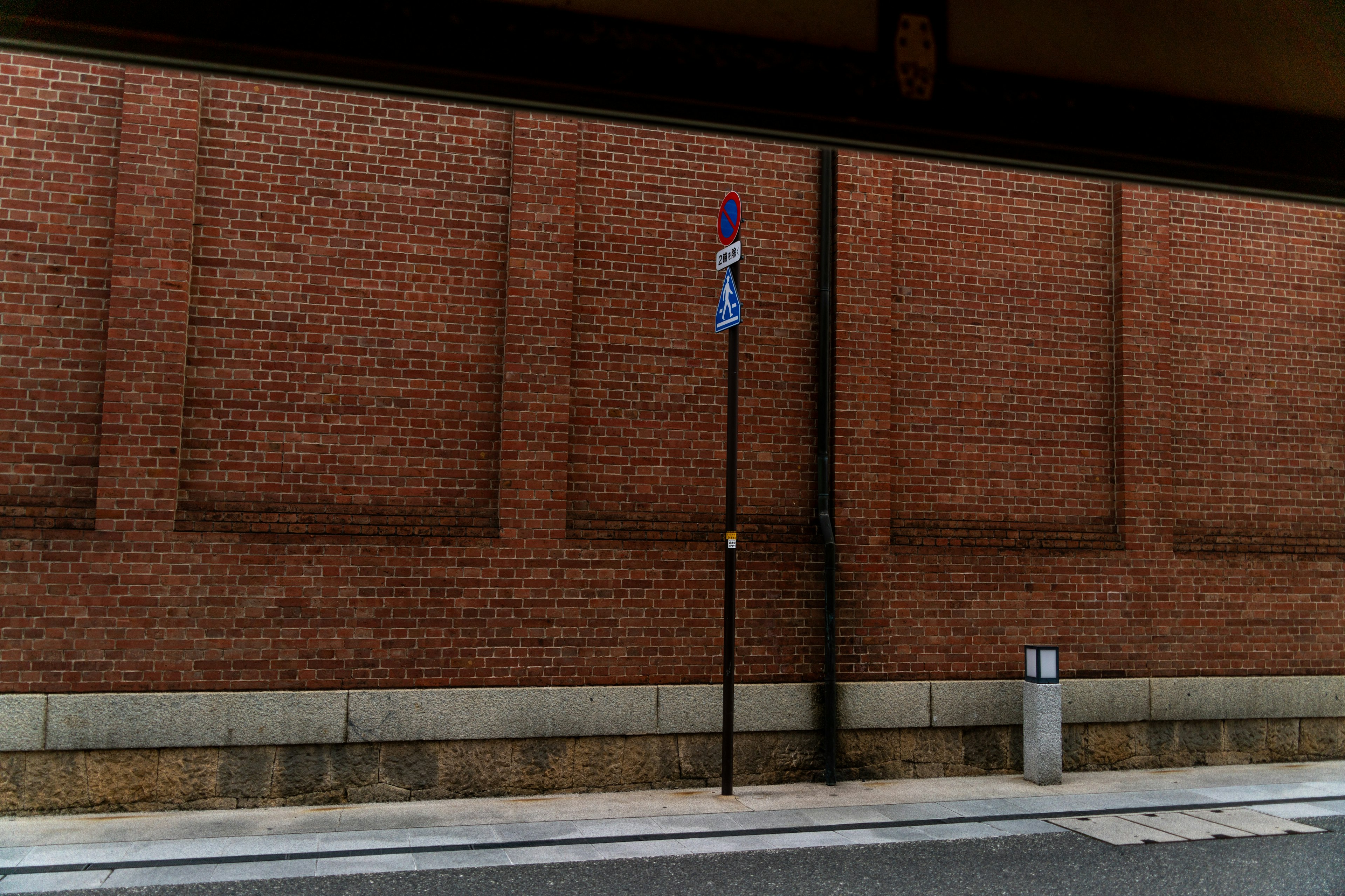 Scena urbana con muro di mattoni e segnale stradale viola