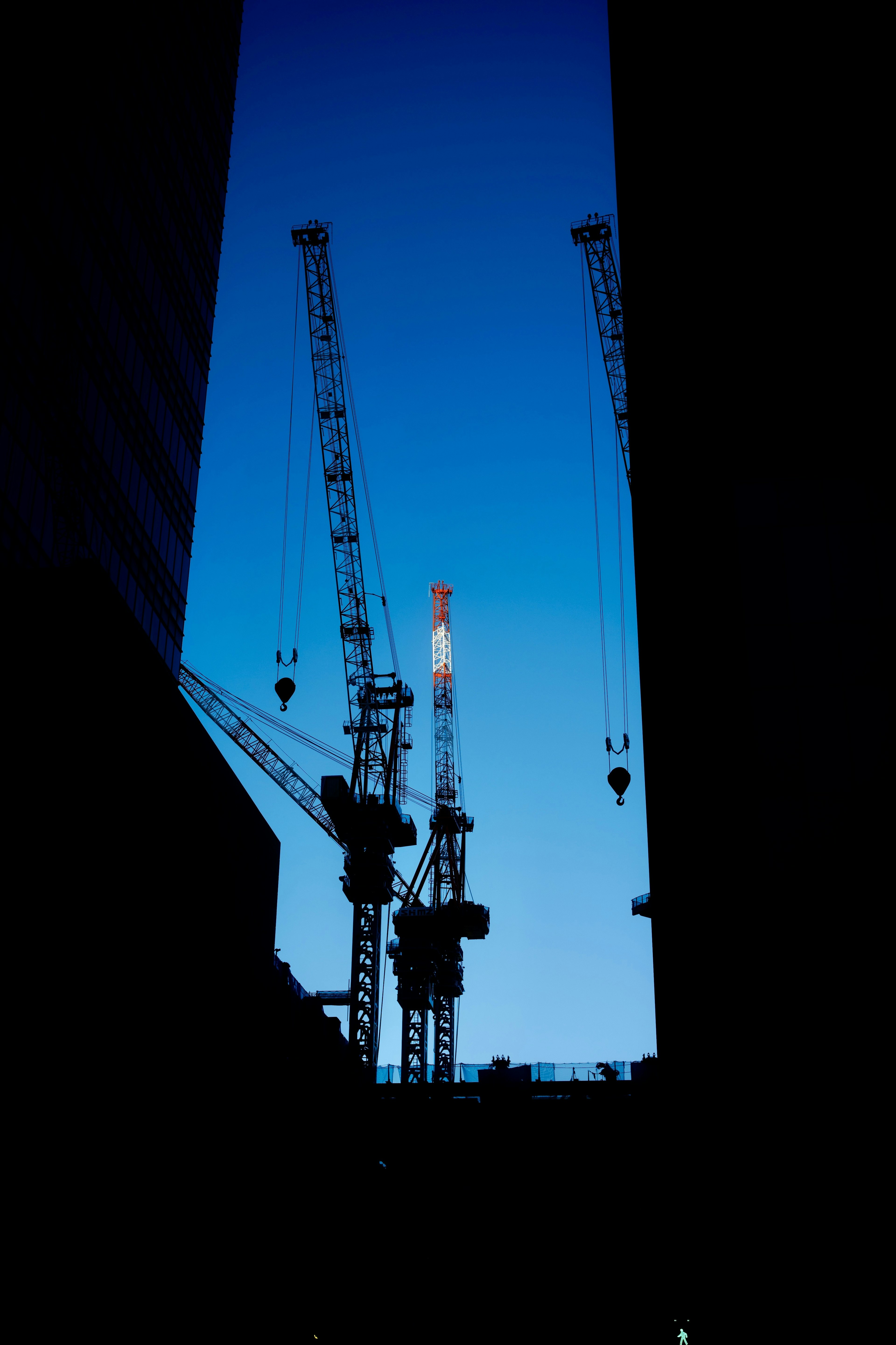 Silhouette von Kränen vor blauem Himmel