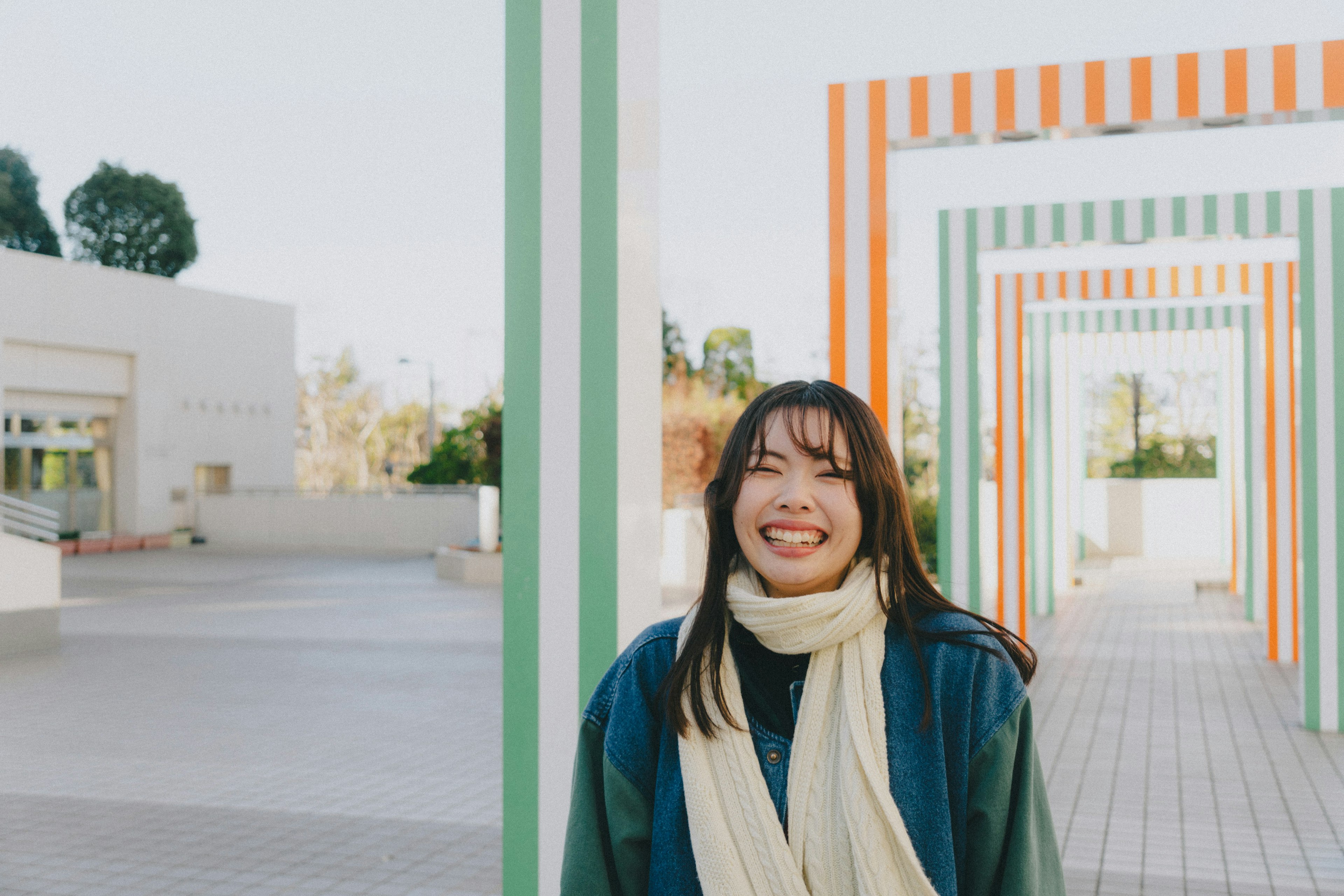 Mujer sonriente frente a arcos a rayas con un fondo brillante