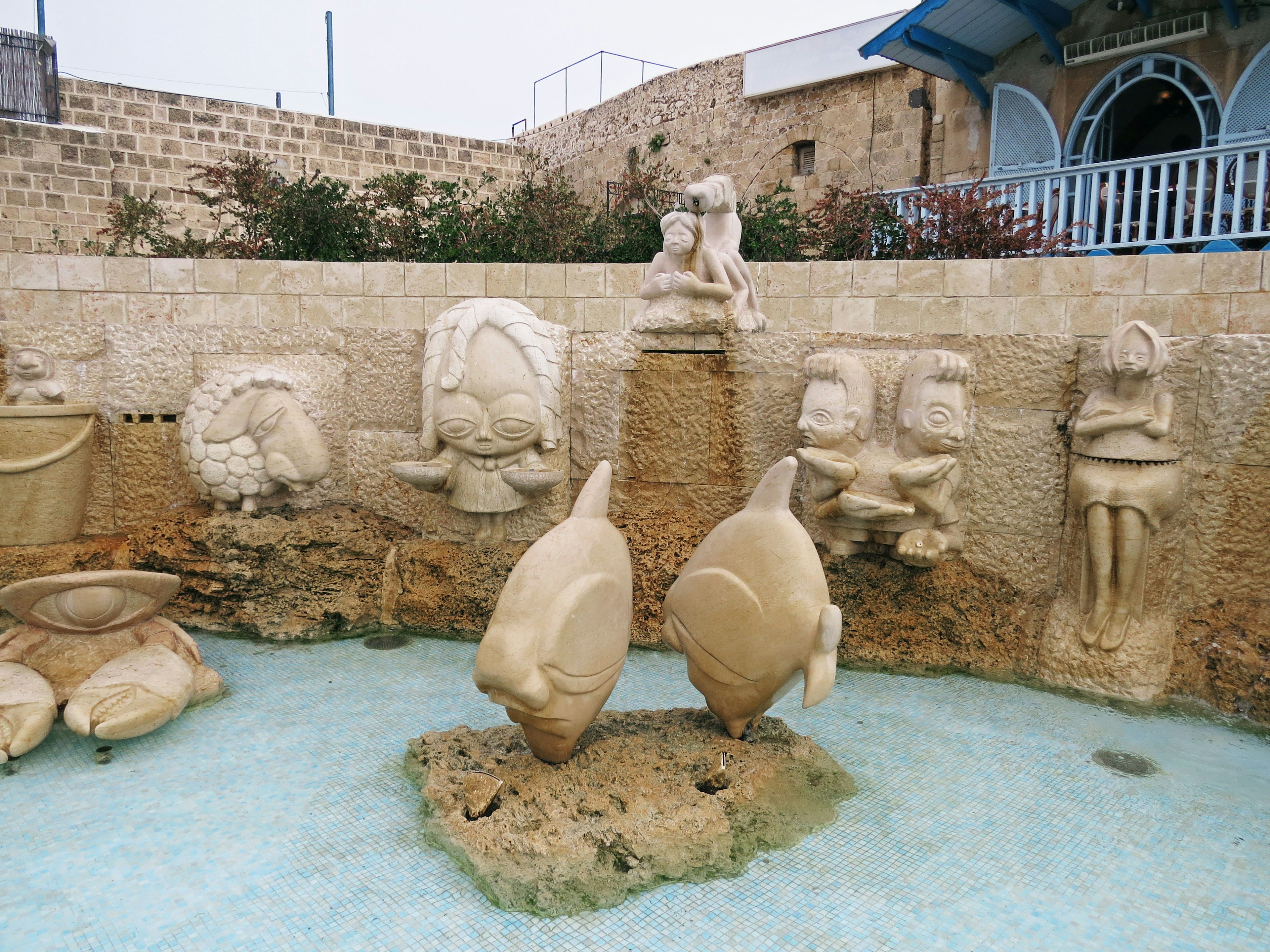 Un estanque con peces tallados y esculturas de pared de piedra