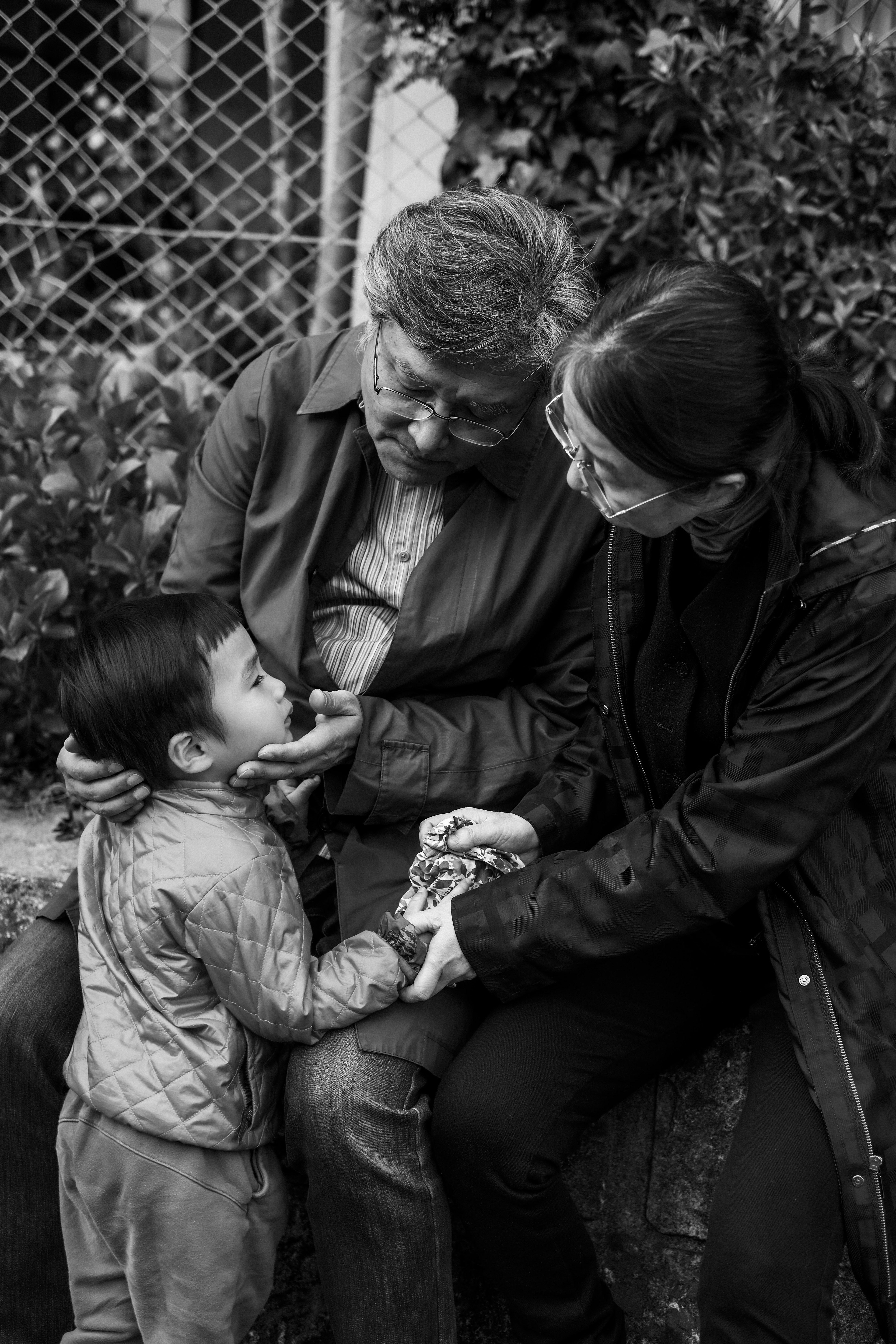 Foto en blanco y negro que captura a un niño y adultos compartiendo un momento íntimo