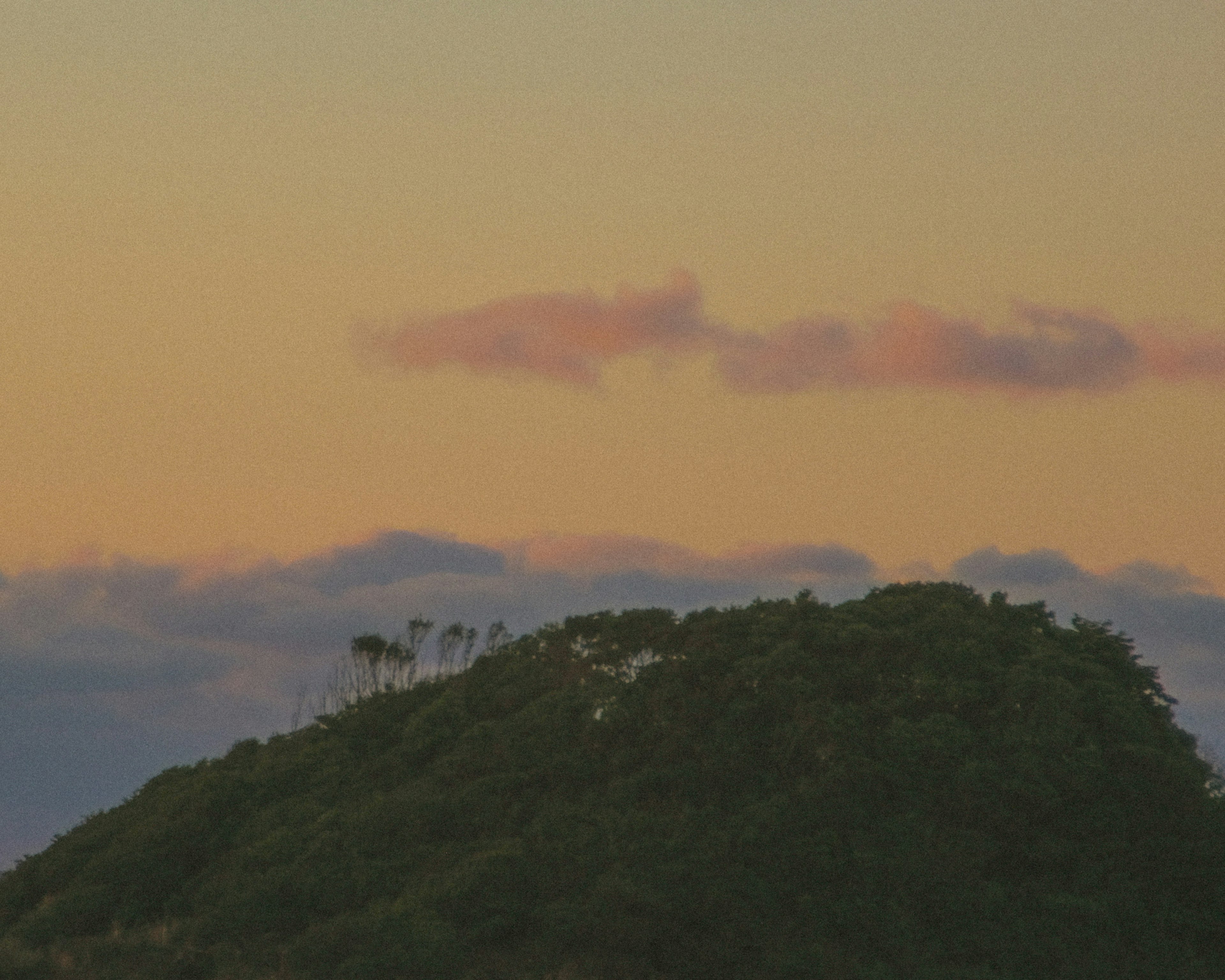 夕焼けの空に浮かぶ小さな丘と雲の景色