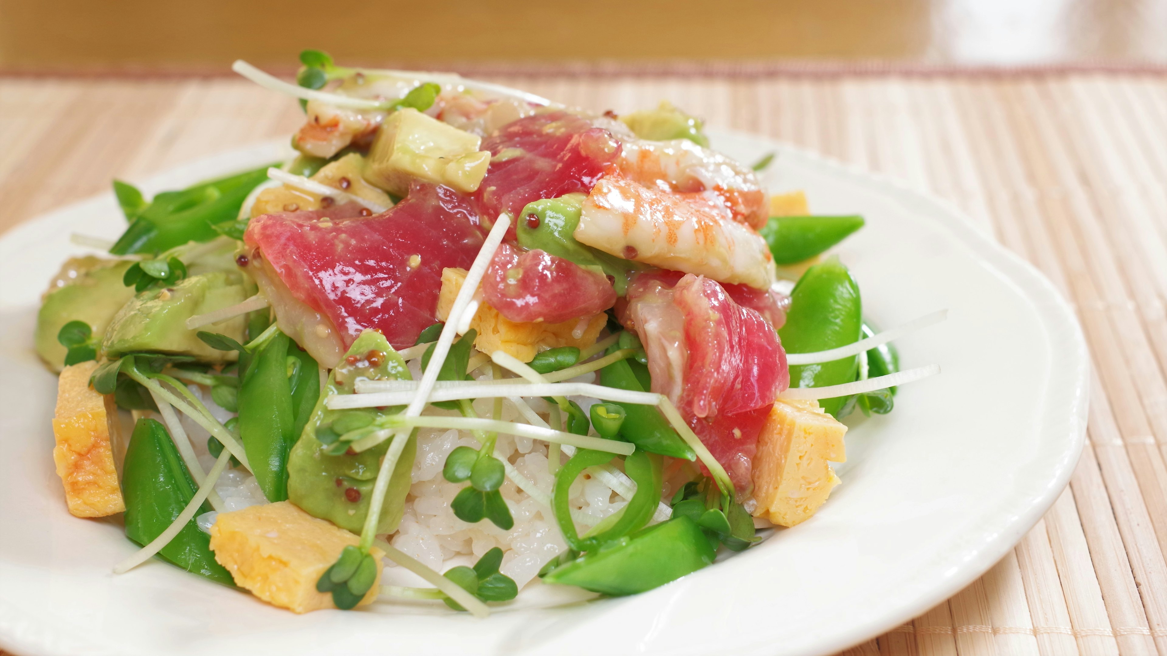 Plato de verduras frescas y sashimi servido sobre arroz