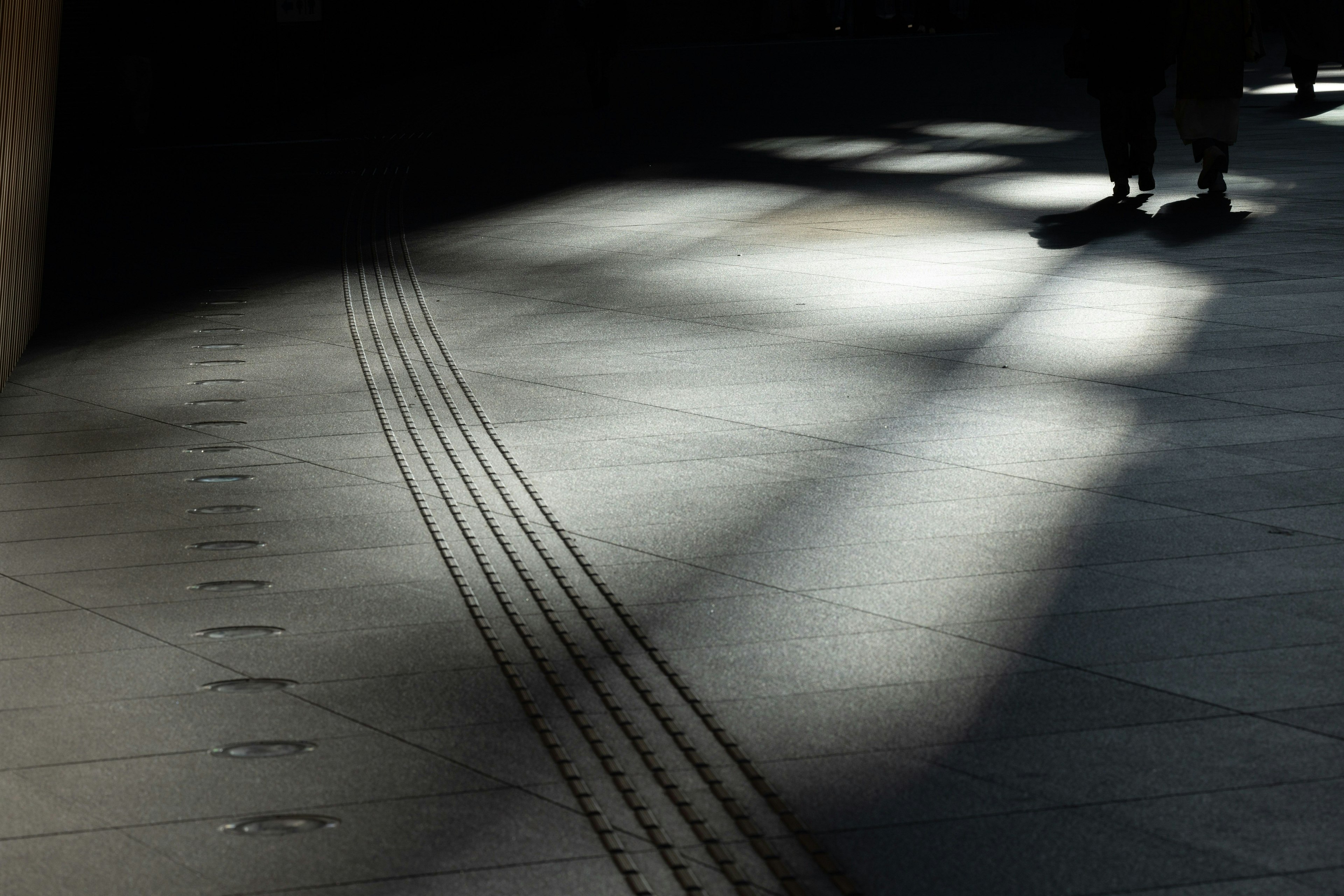 Contrasto di luce e ombra sul pavimento con linee e piedi di una persona