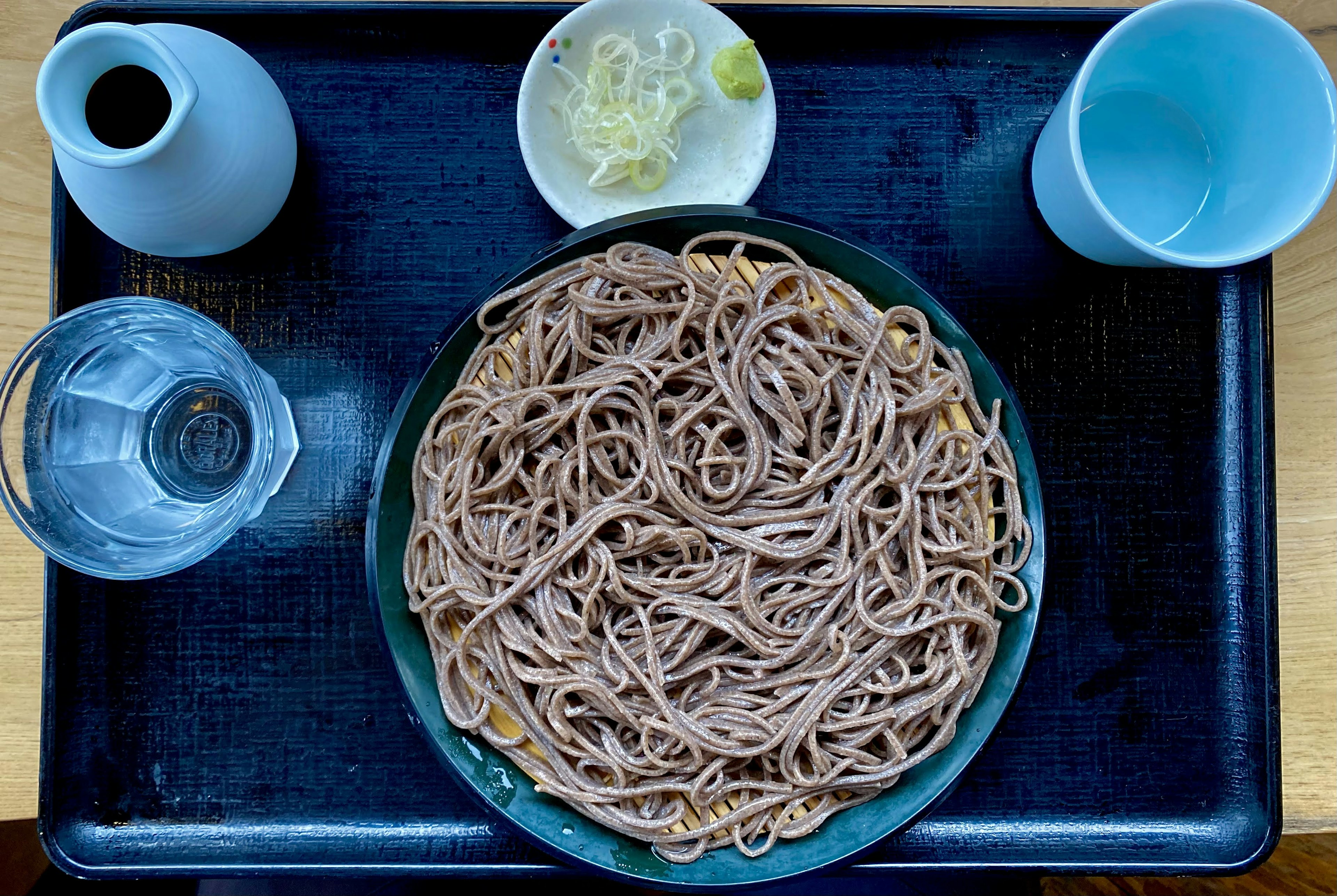 Plate of soba noodles with condiments and drinks