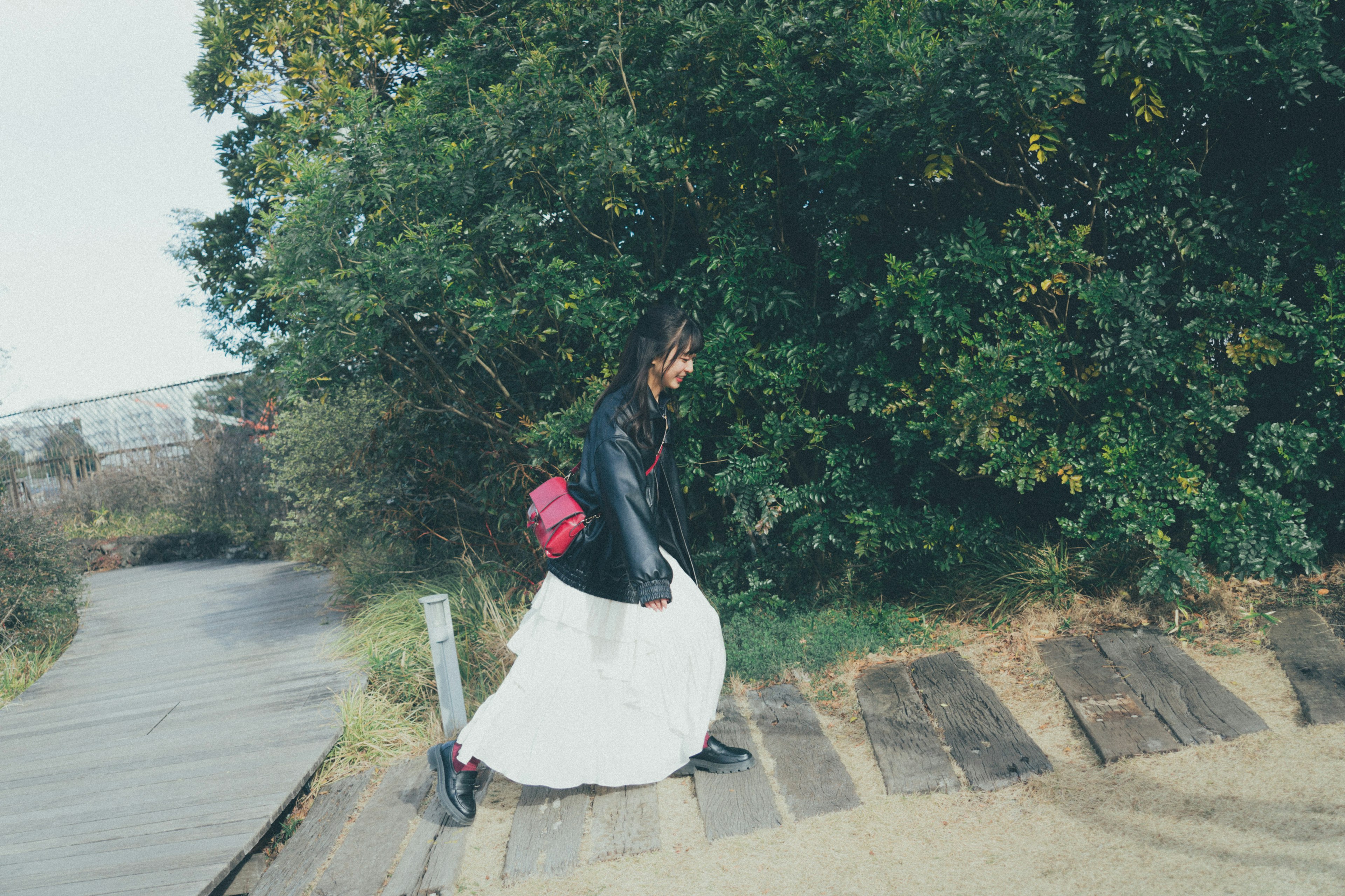 A woman walking in a white skirt against a green backdrop