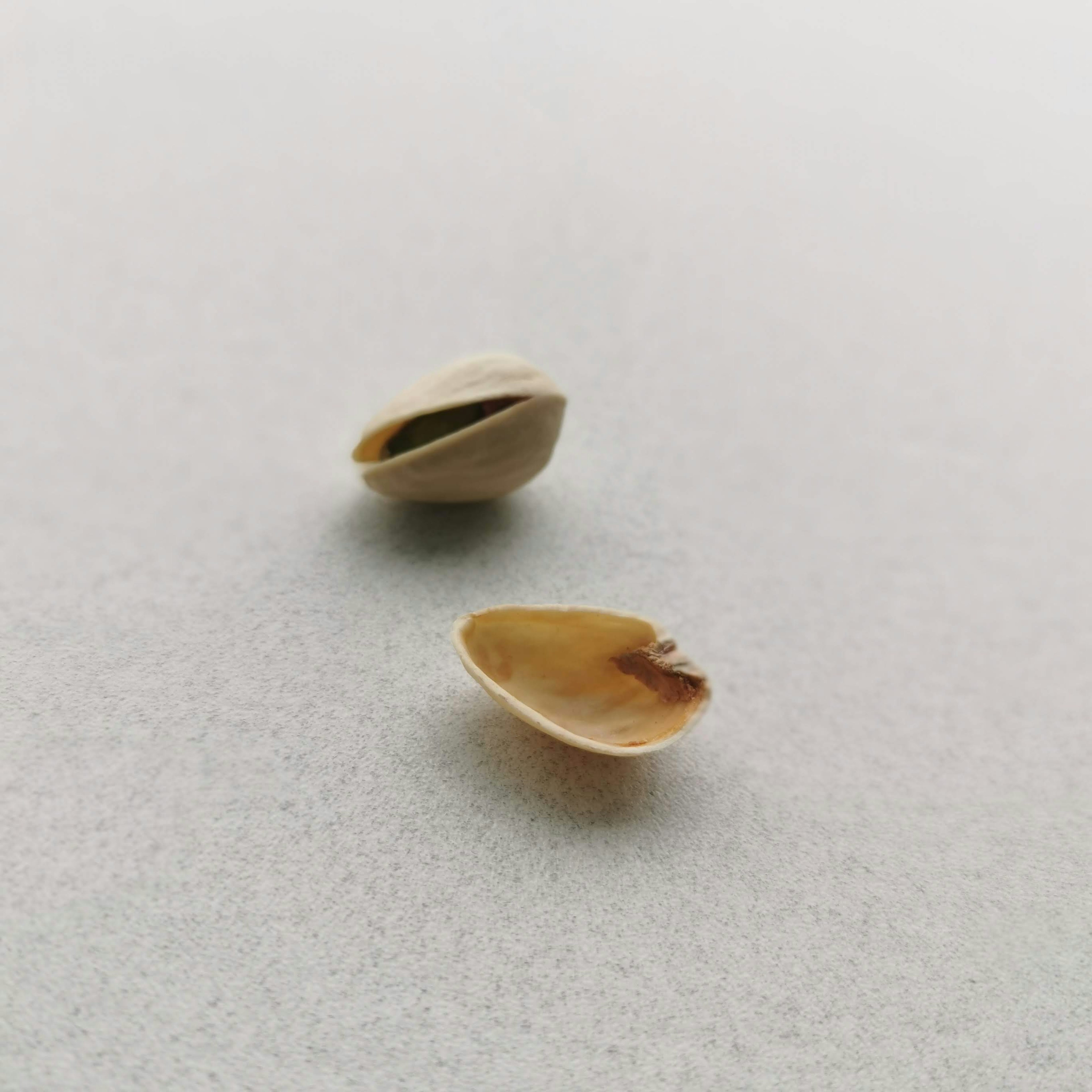 Two open pistachio shells placed on a white surface