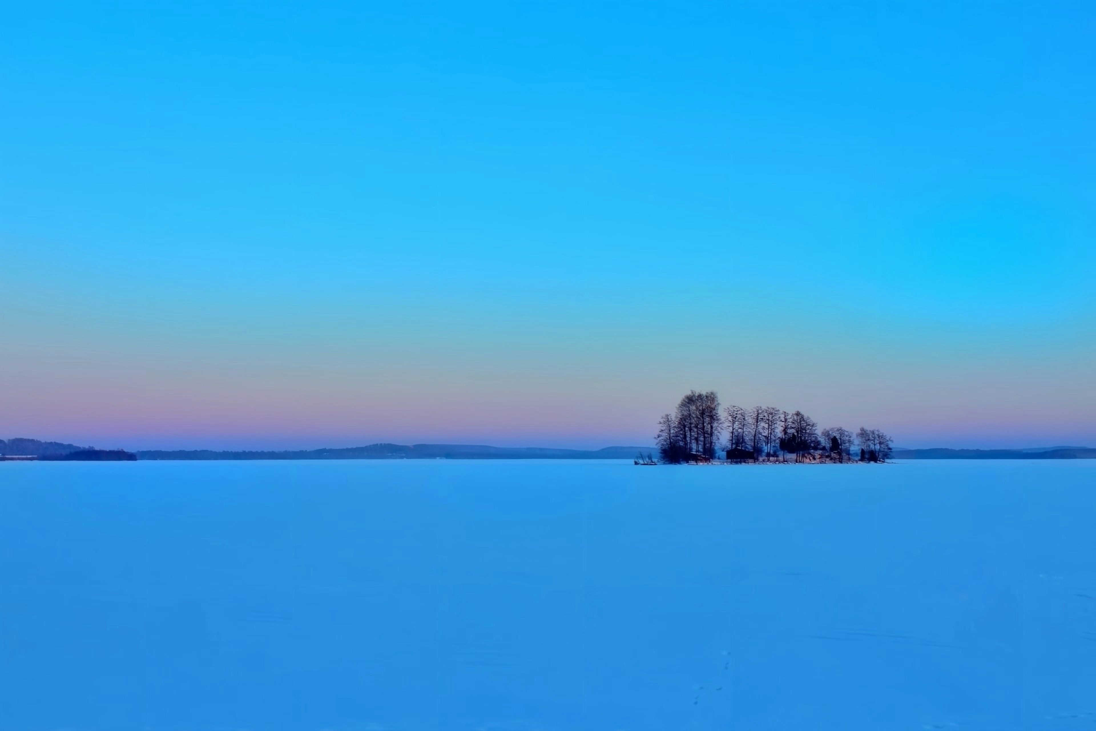 Isla aislada en un lago cubierto de nieve con un cielo colorido